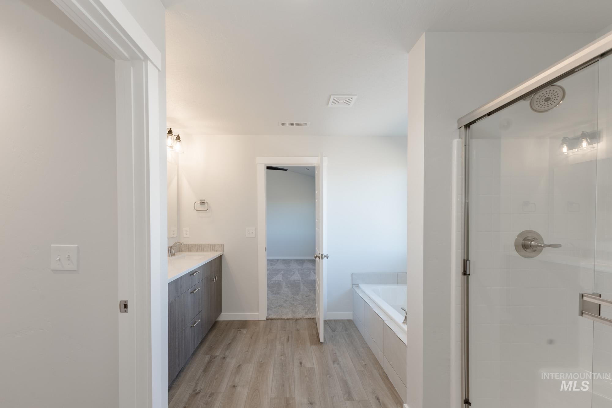 Bathroom with vanity, light wood finished floors, a garden tub, and a stall shower