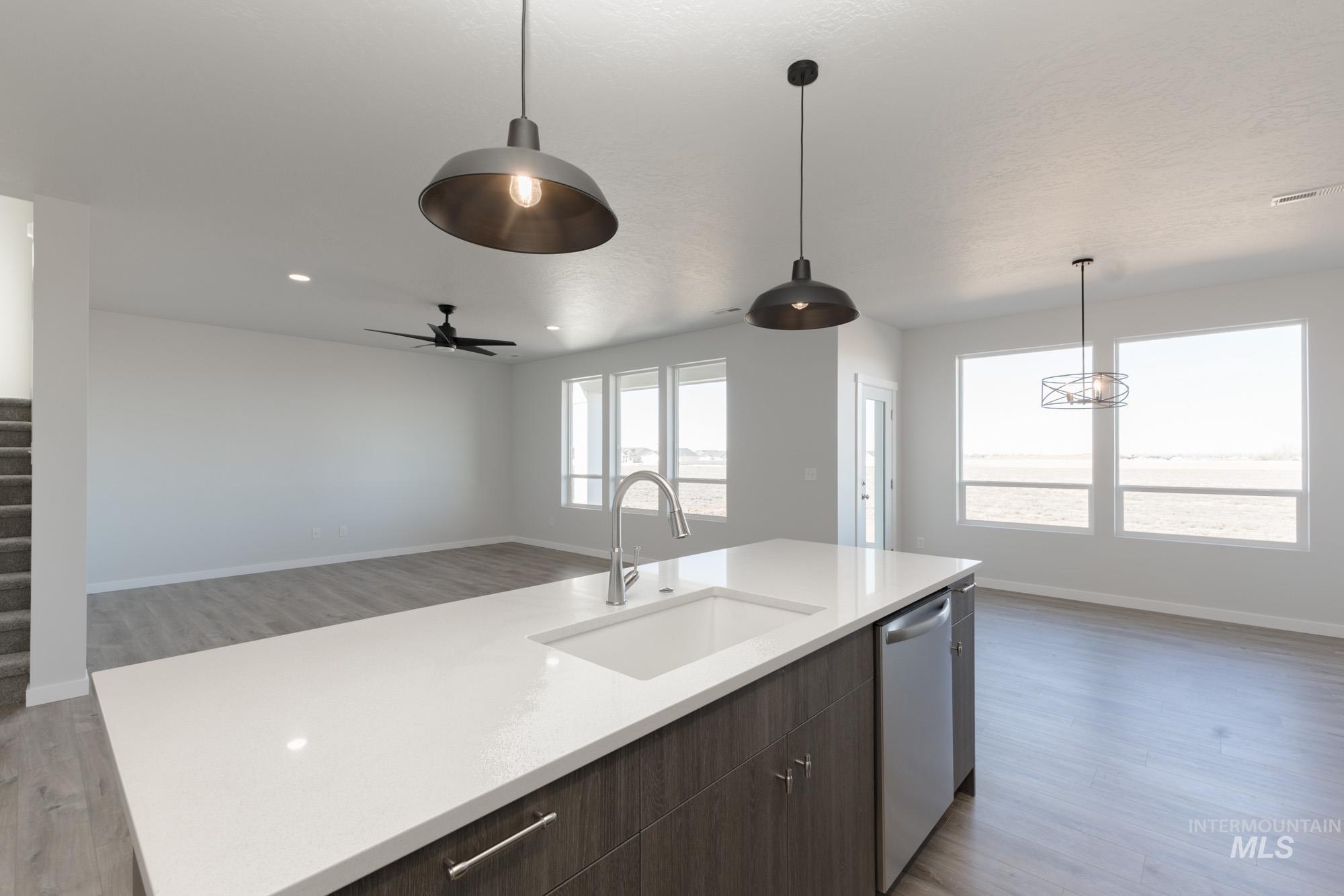 Kitchen featuring dark brown cabinetry, light wood finished floors, open floor plan, dishwasher, and recessed lighting