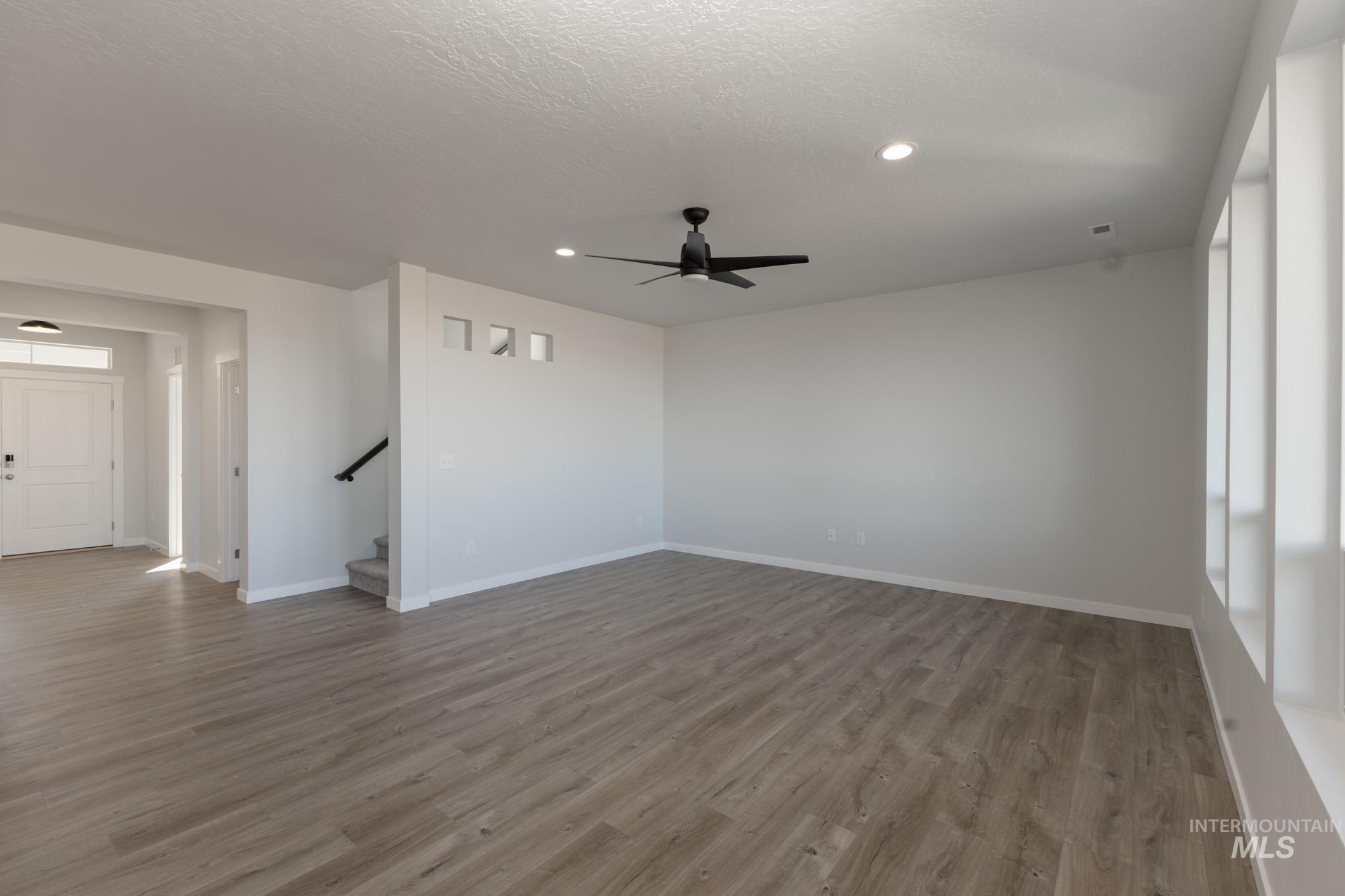 Unfurnished room with light wood-style floors, a ceiling fan, recessed lighting, a textured ceiling, and stairs