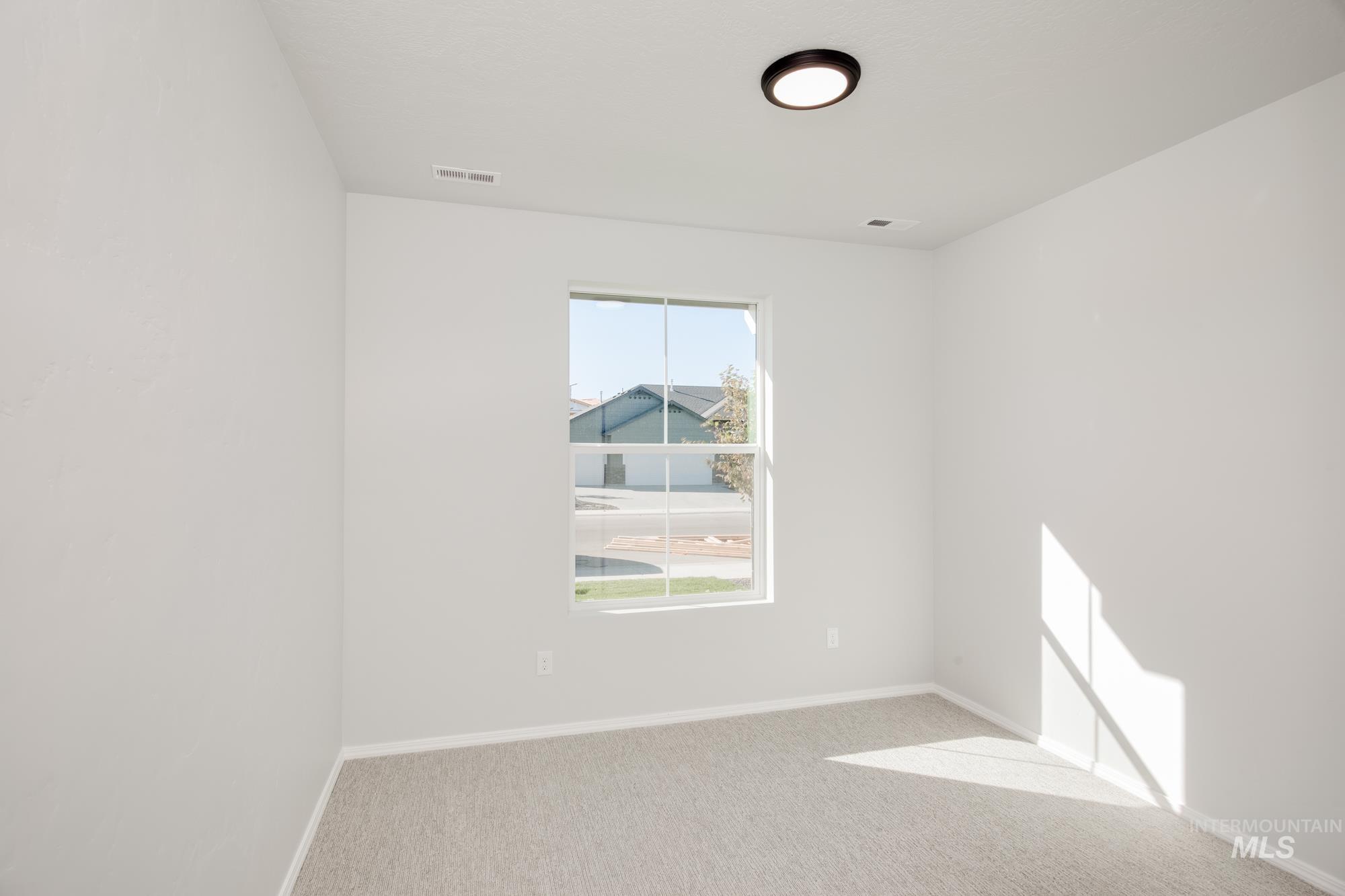 Empty room with light colored carpet and baseboards