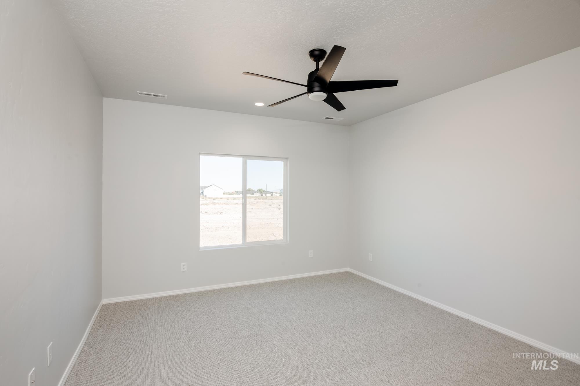 Empty room with light colored carpet and a ceiling fan