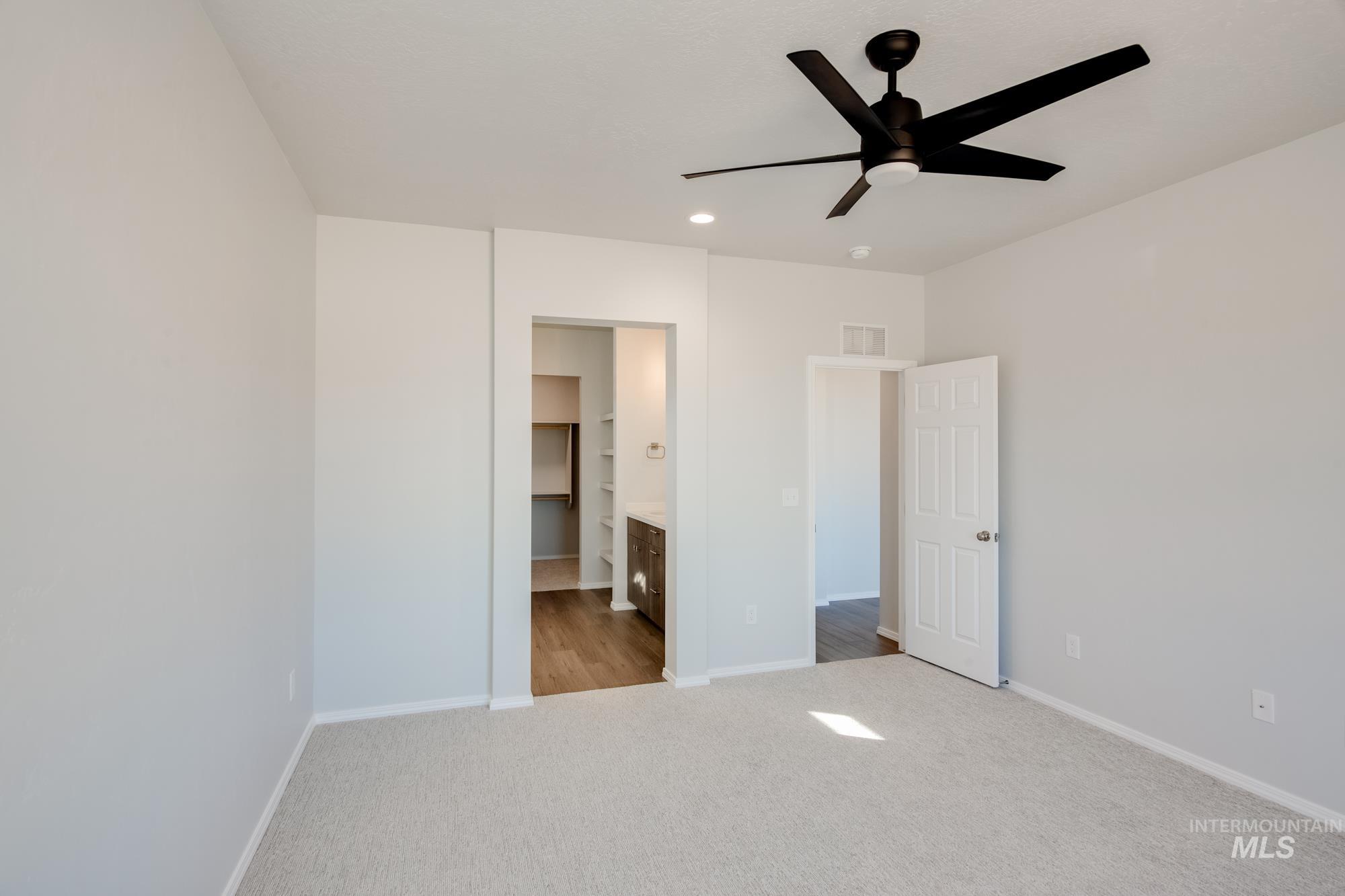 Unfurnished bedroom featuring light carpet, ensuite bathroom, a ceiling fan, and recessed lighting