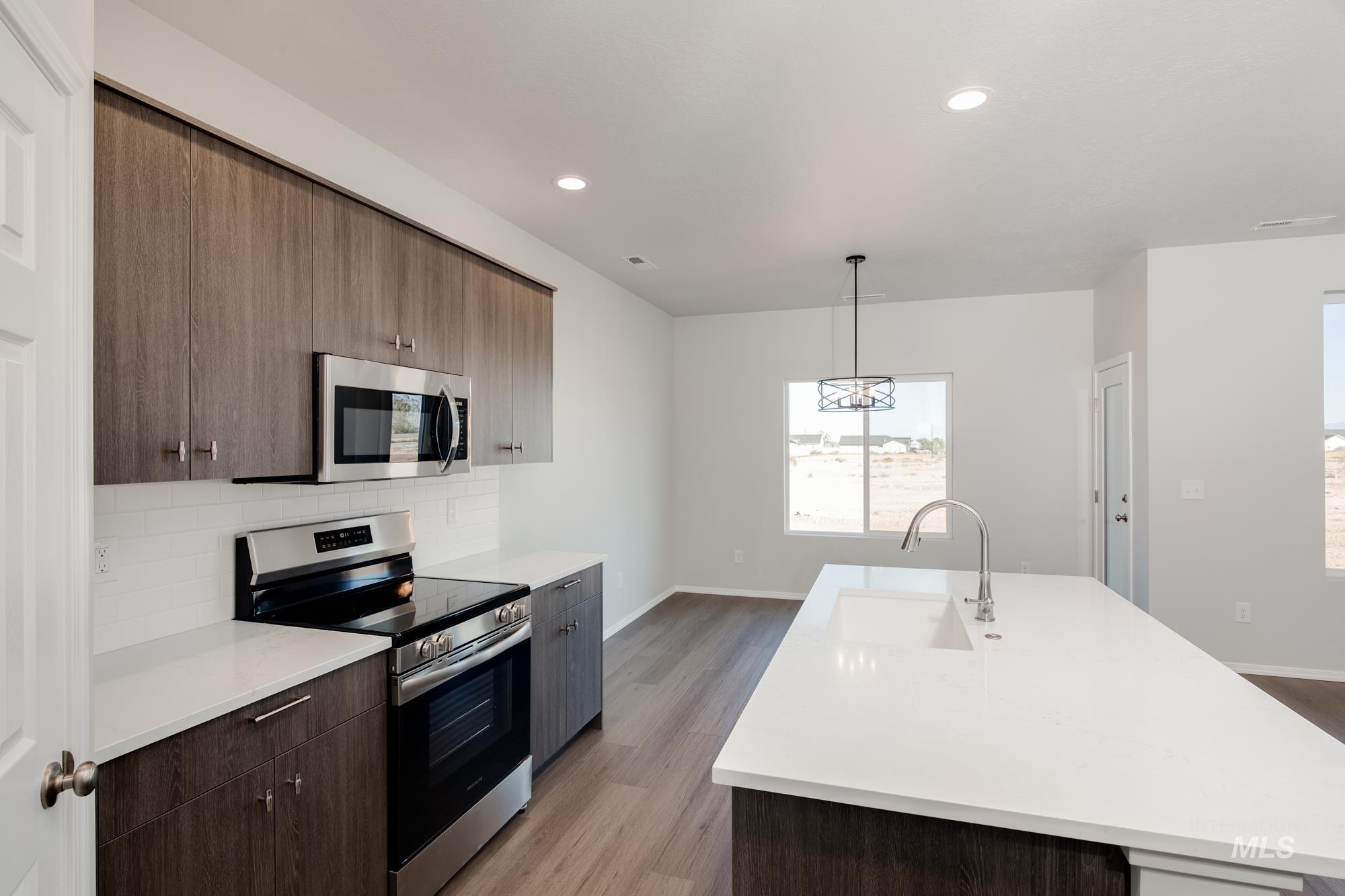 Kitchen featuring appliances with stainless steel finishes, an island with sink, decorative light fixtures, recessed lighting, and modern cabinets