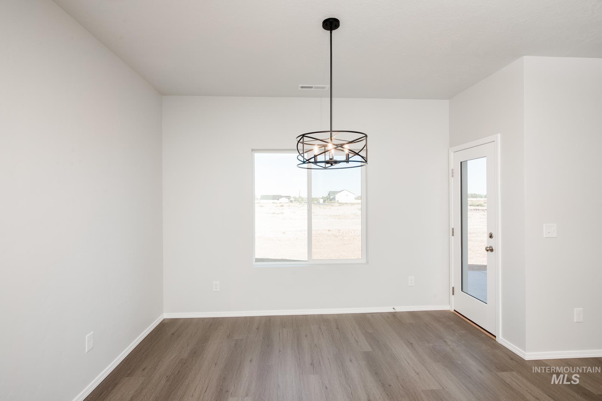 Unfurnished dining area with a chandelier and wood finished floors
