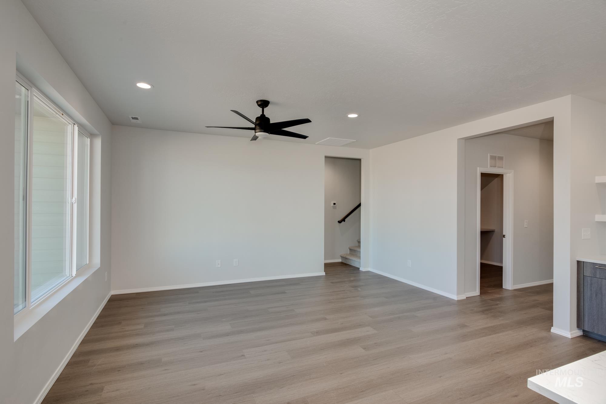 Unfurnished room with light wood-style flooring, stairs, ceiling fan, and recessed lighting