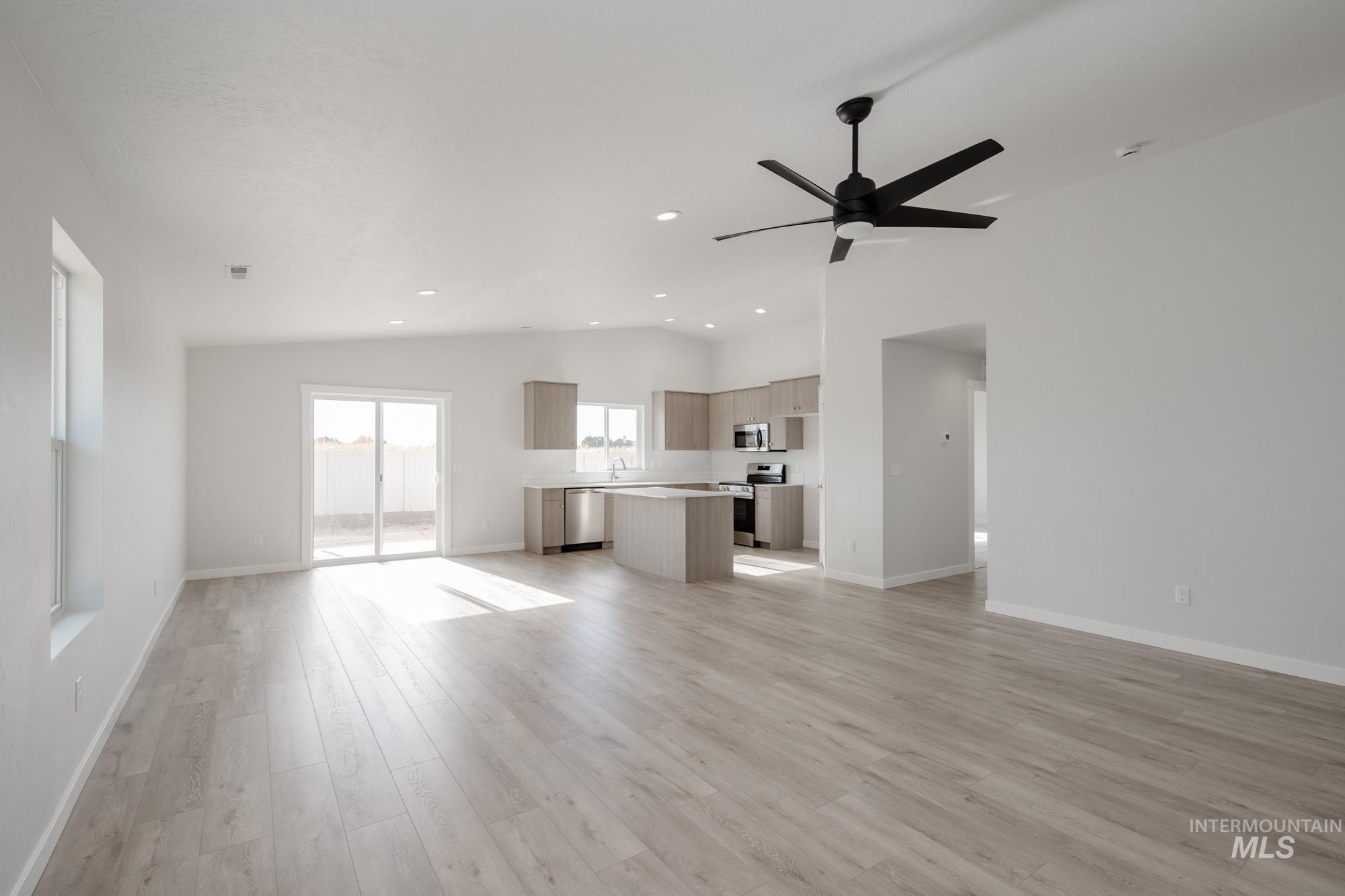 Unfurnished living room featuring vaulted ceiling, light wood-style flooring, recessed lighting, and ceiling fan