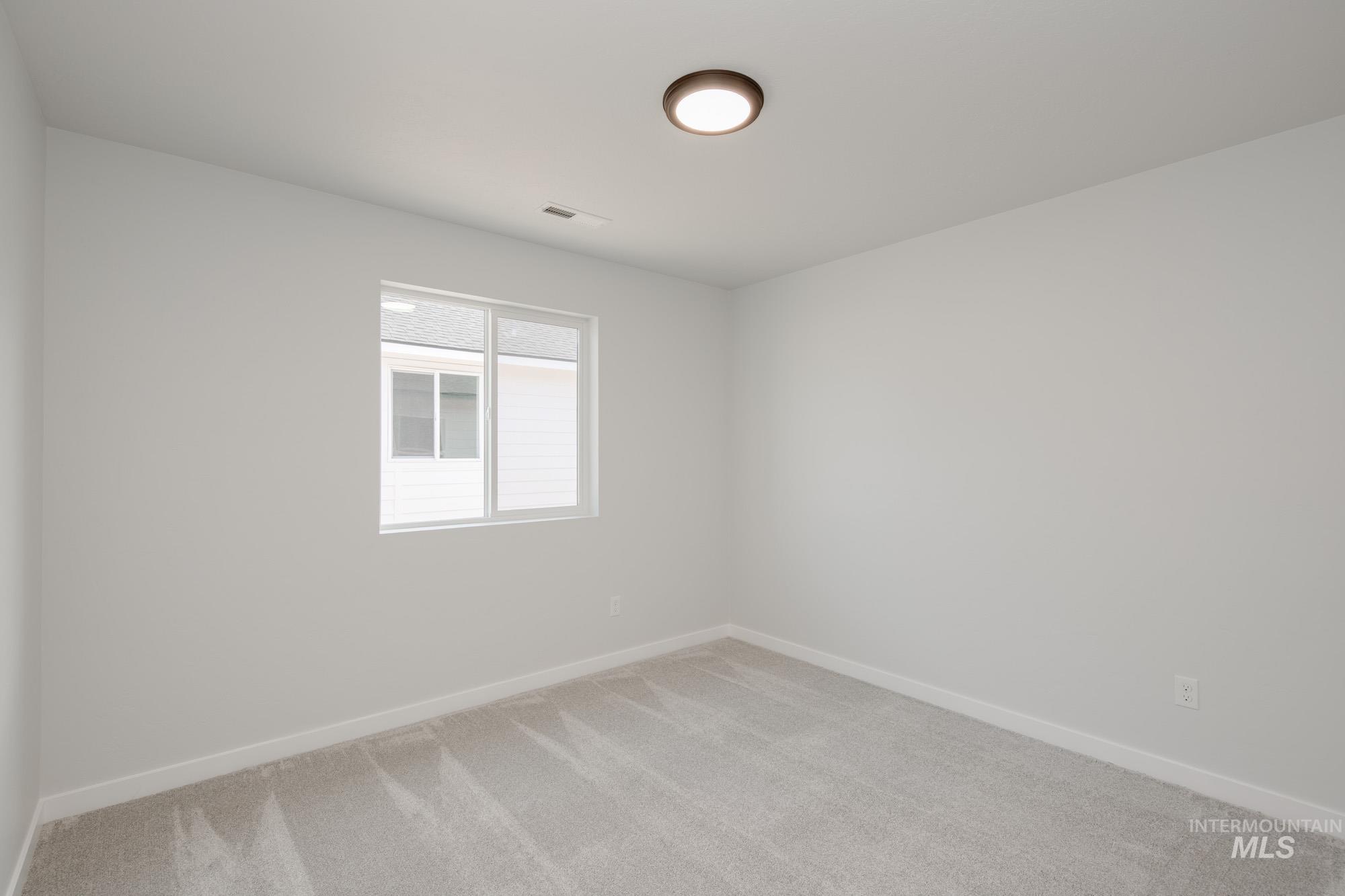 Spare room featuring light carpet and baseboards