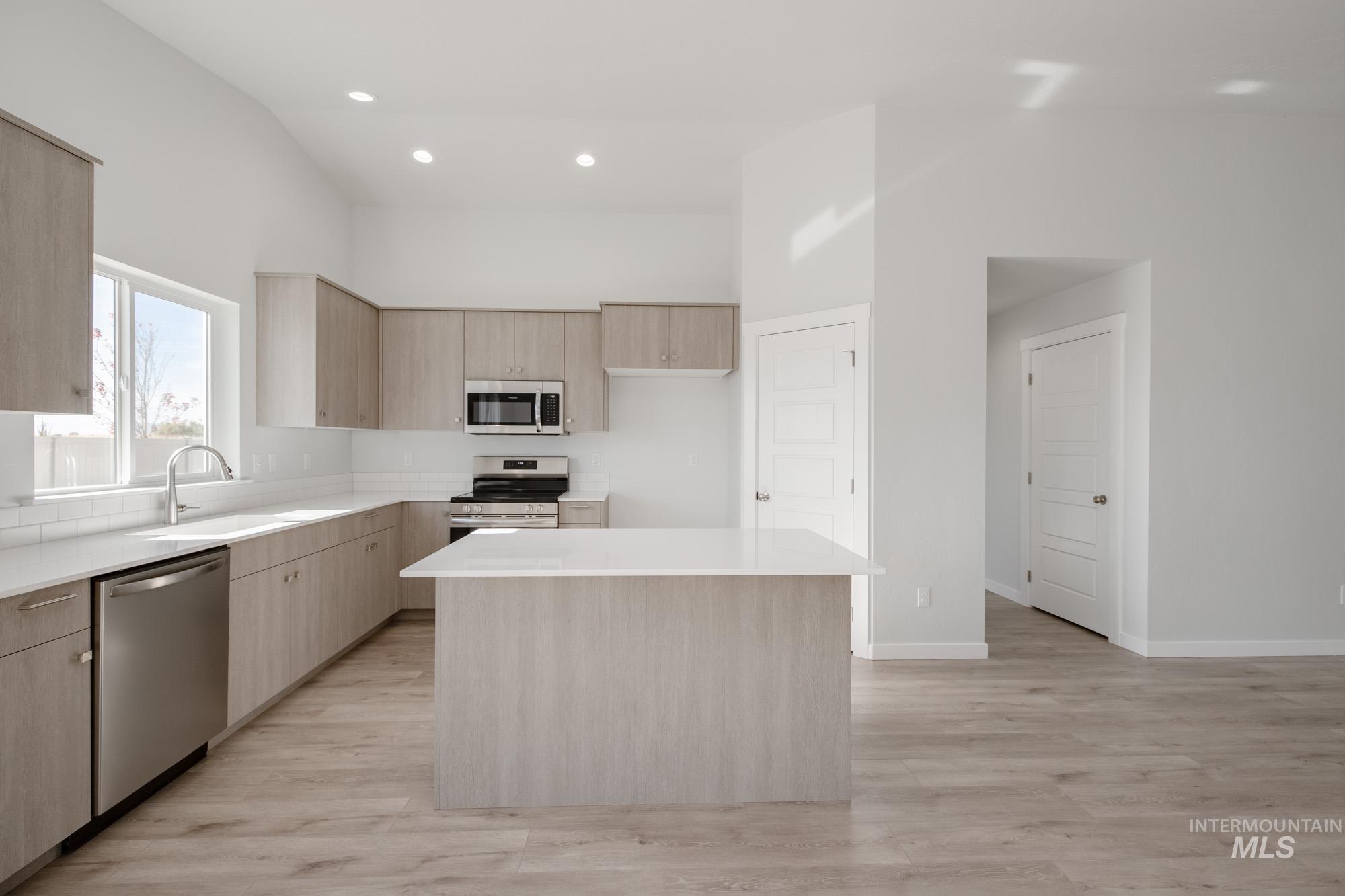 Kitchen with light brown cabinets, modern cabinets, stainless steel appliances, recessed lighting, and light stone counters