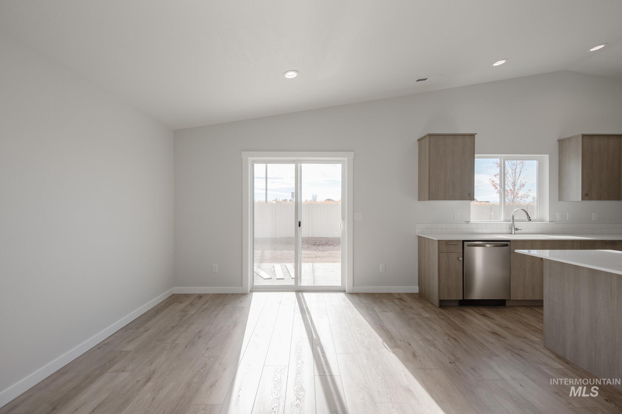 Kitchen featuring lofted ceiling, modern cabinets, plenty of natural light, stainless steel dishwasher, and recessed lighting