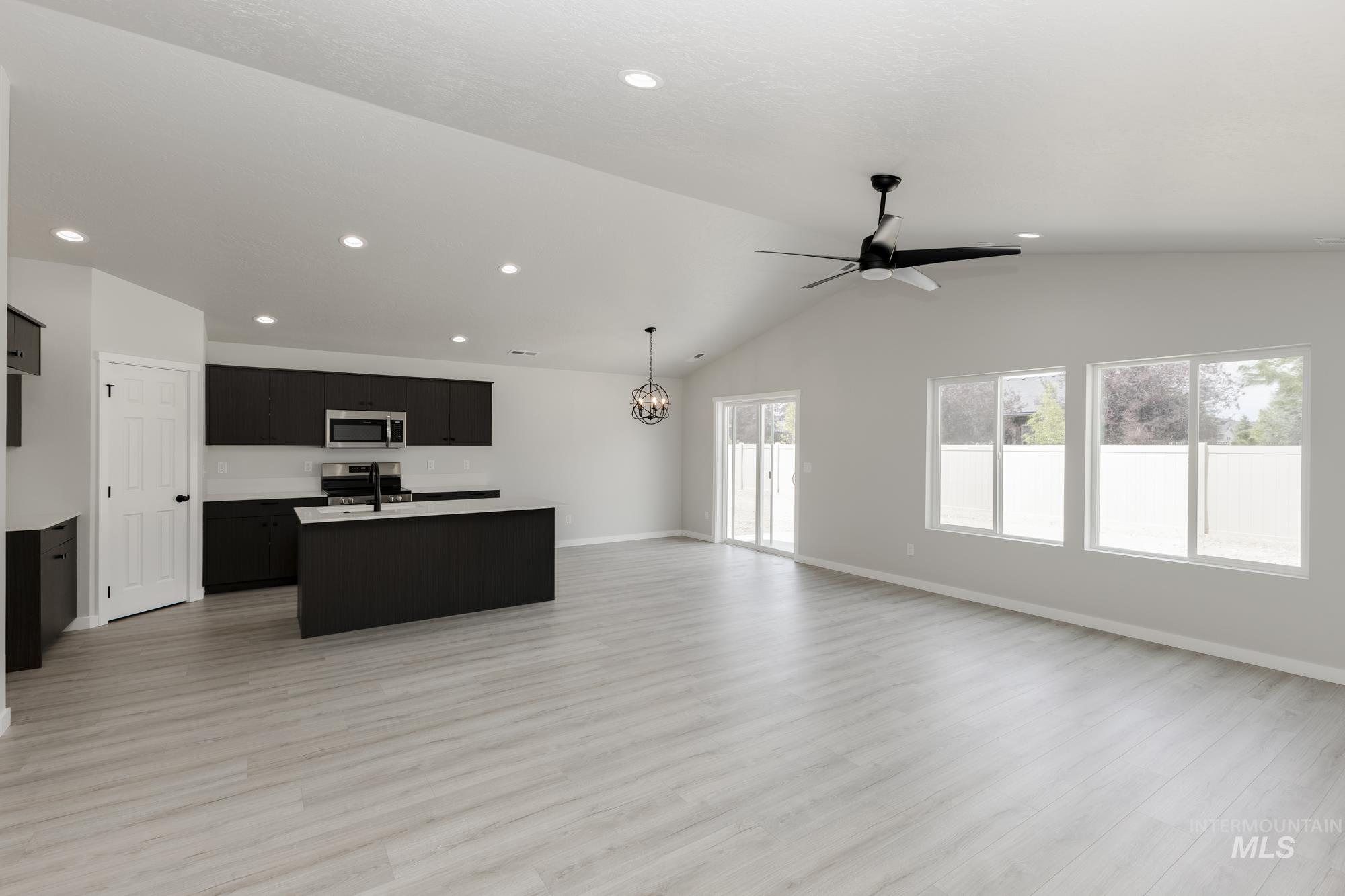 Kitchen with open floor plan, an island with sink, dark cabinets, appliances with stainless steel finishes, and recessed lighting