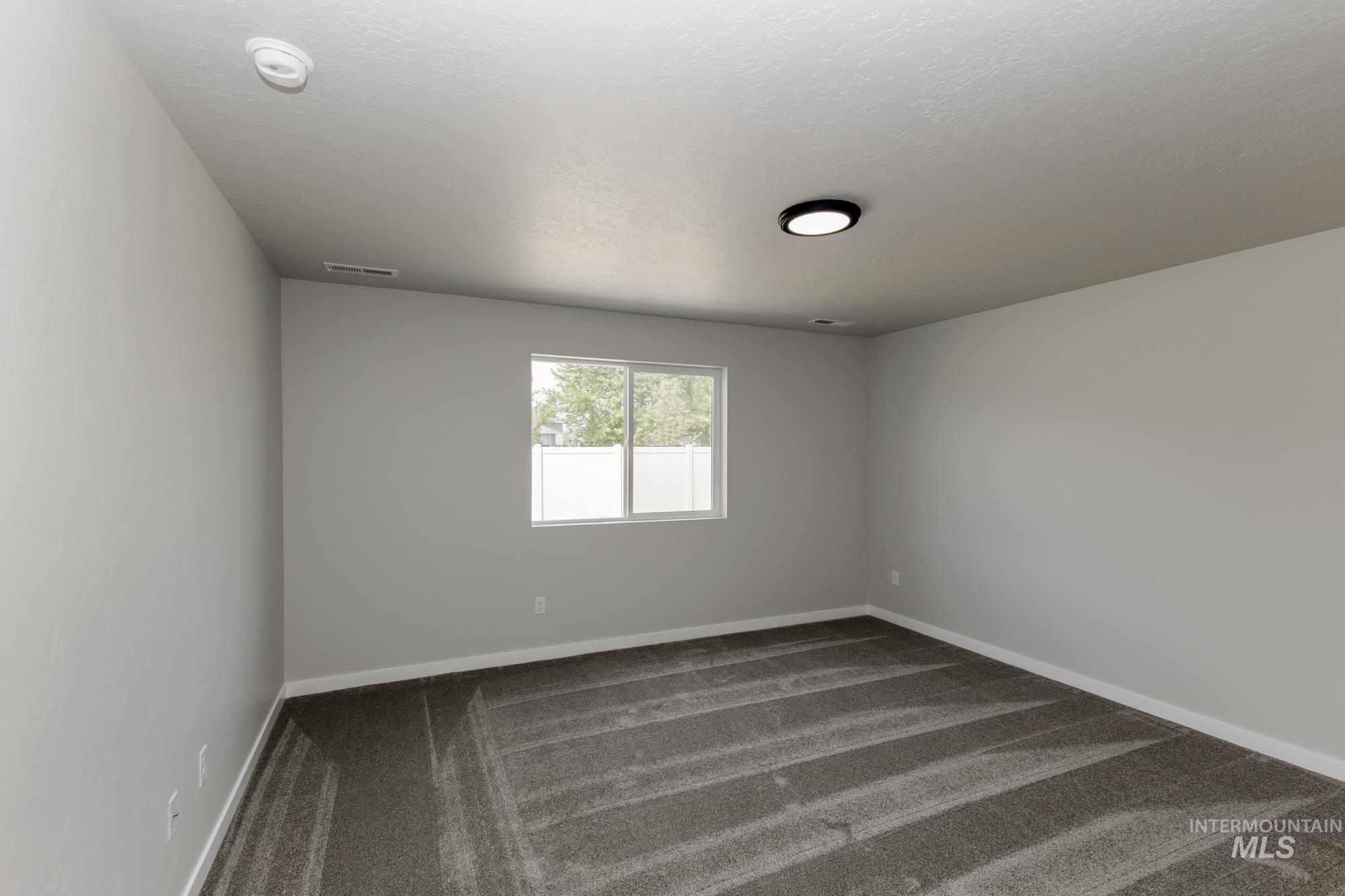 Spare room featuring dark colored carpet and a textured ceiling