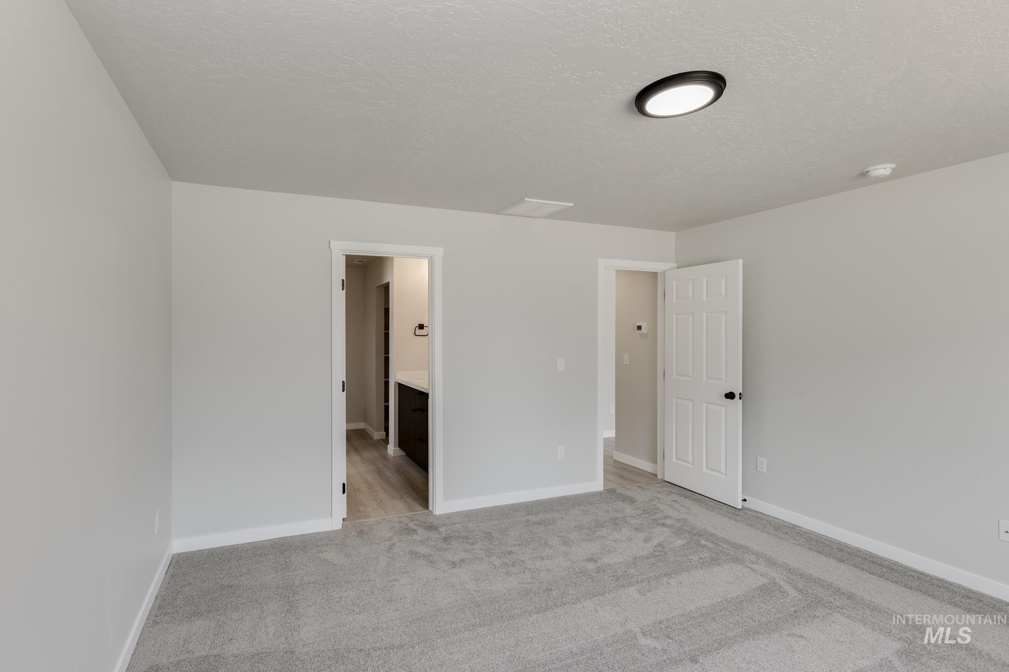 Empty room featuring a textured ceiling and light carpet