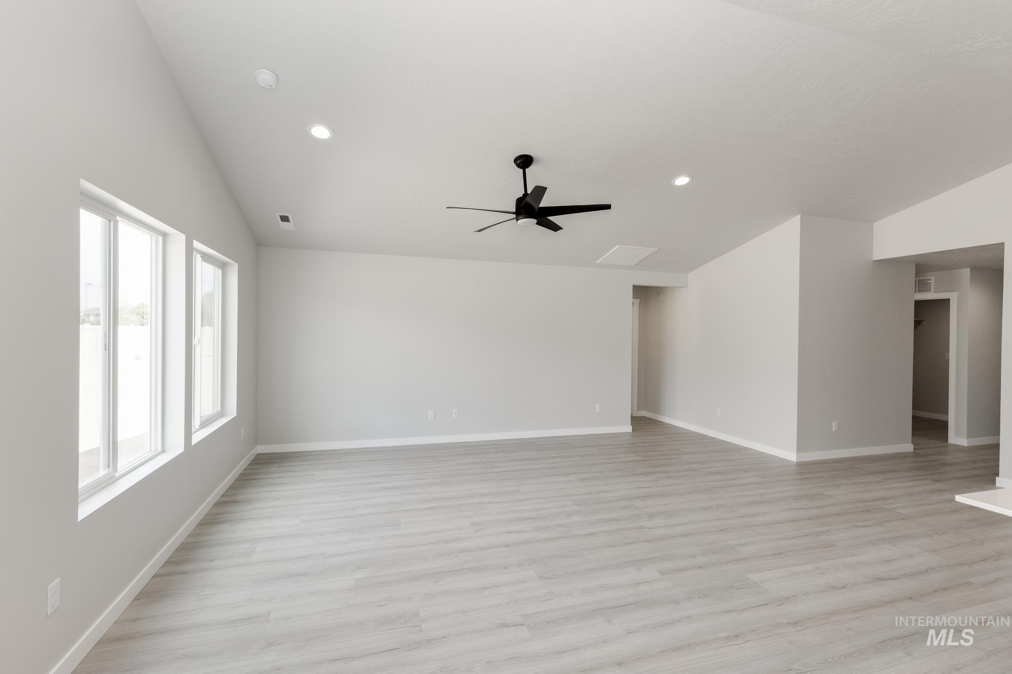 Spare room with lofted ceiling, light wood-style floors, ceiling fan, and recessed lighting