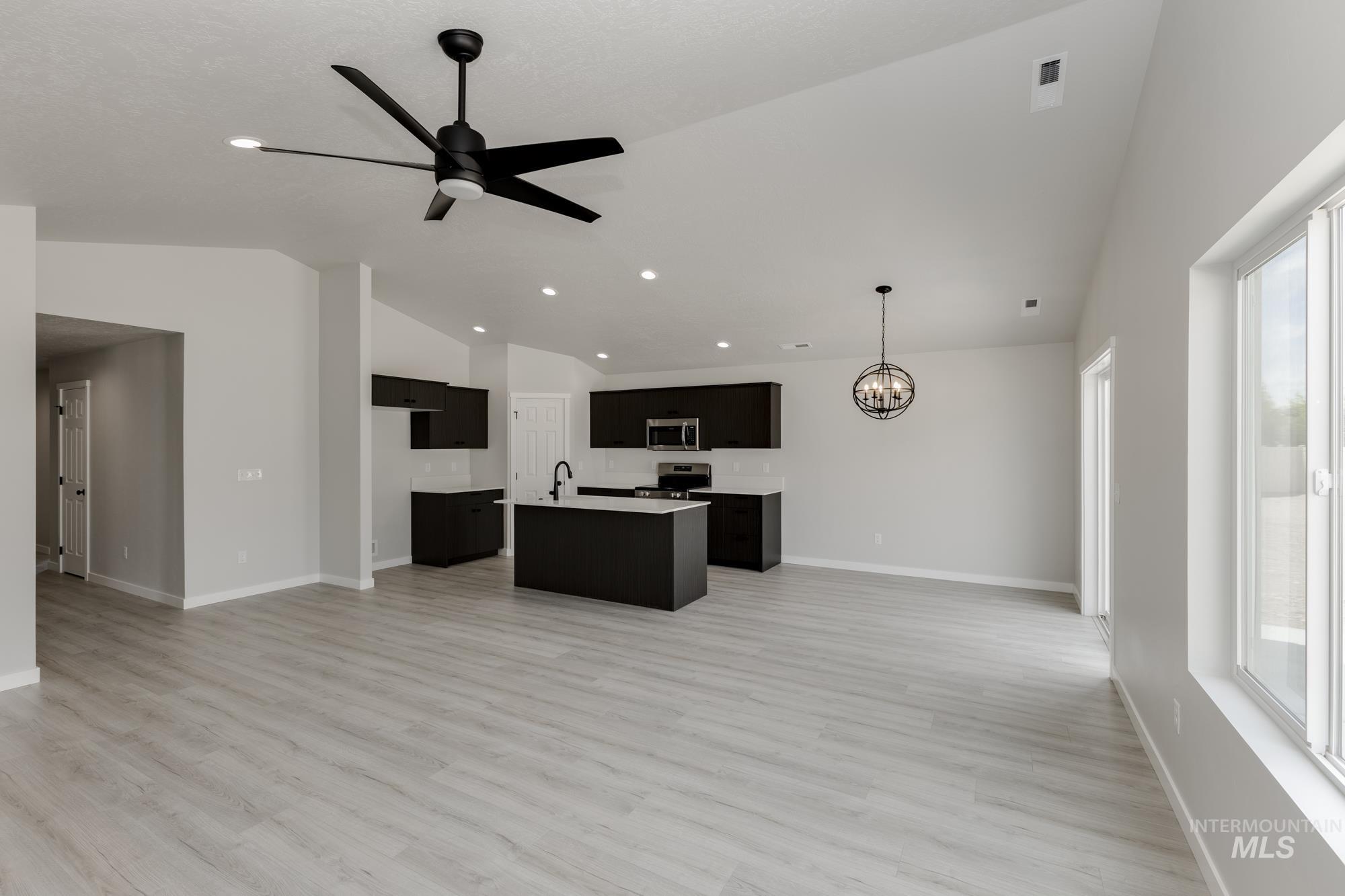 Kitchen featuring open floor plan, lofted ceiling, light countertops, dark cabinets, and a chandelier