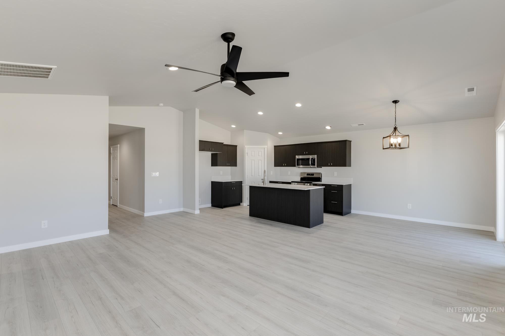 Kitchen with open floor plan, light countertops, light wood-type flooring, lofted ceiling, and stainless steel appliances