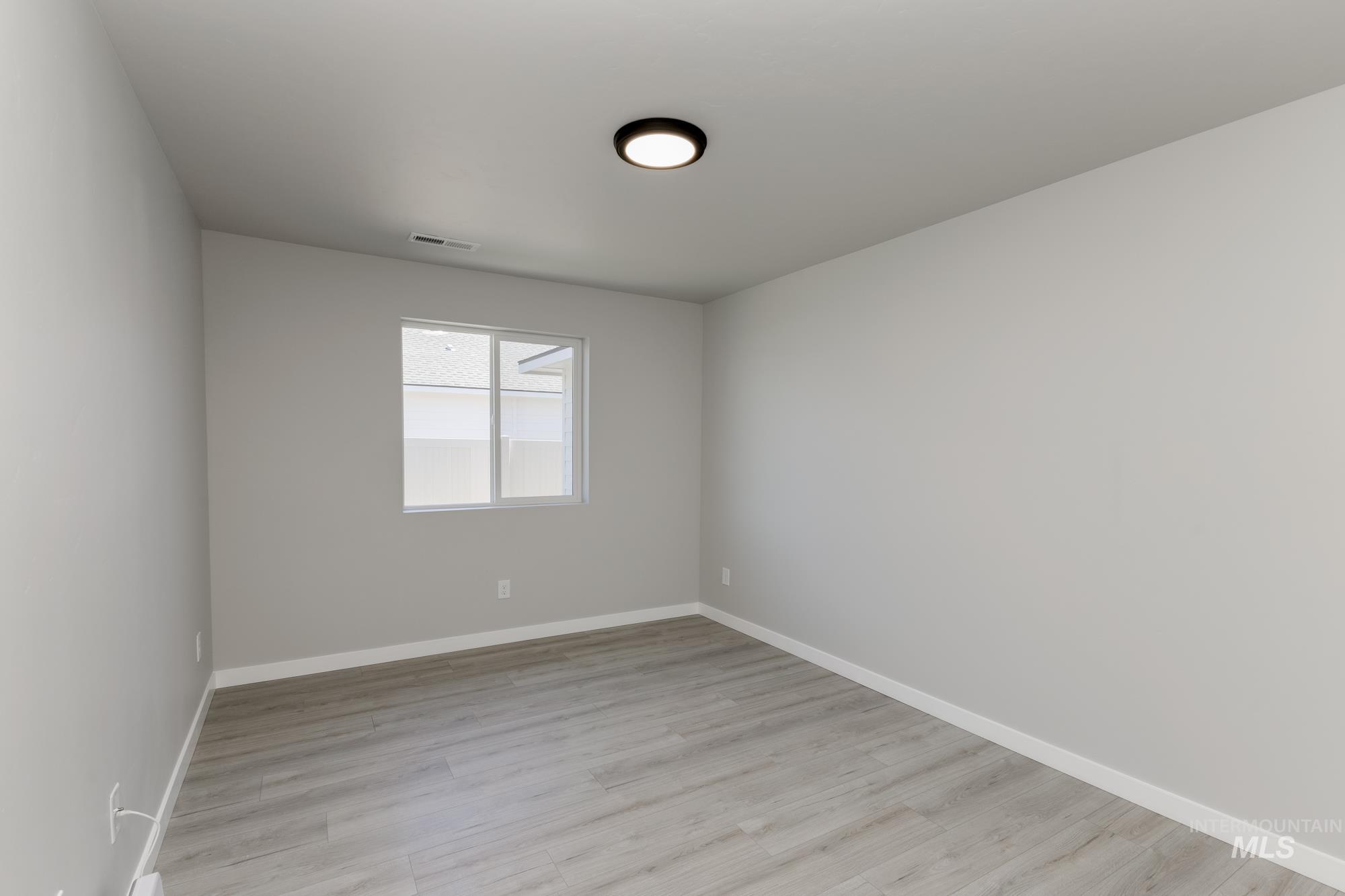Spare room featuring light wood finished floors and baseboards