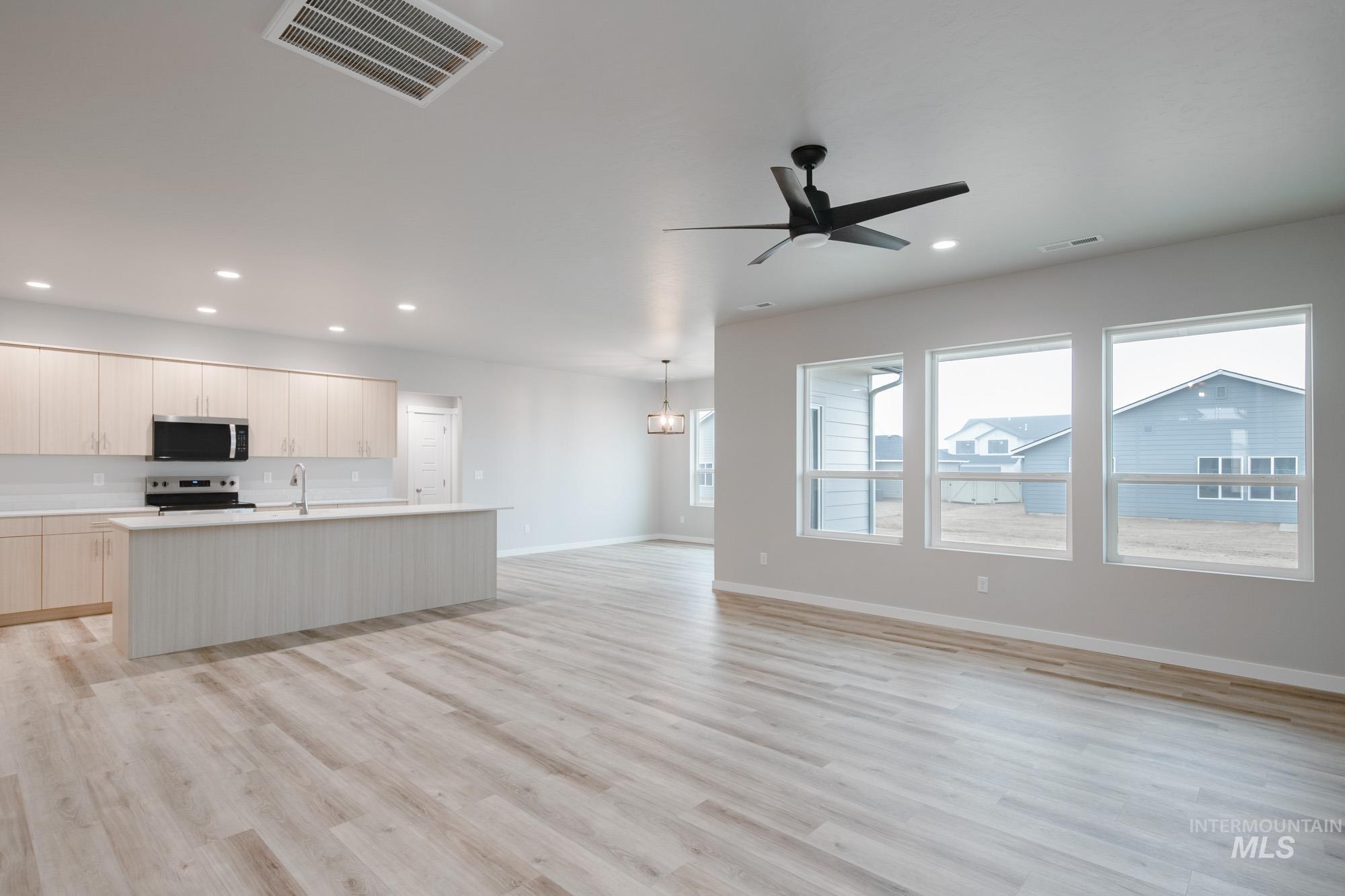 Kitchen with an island with sink, light wood-style floors, open floor plan, stainless steel appliances, and modern cabinets