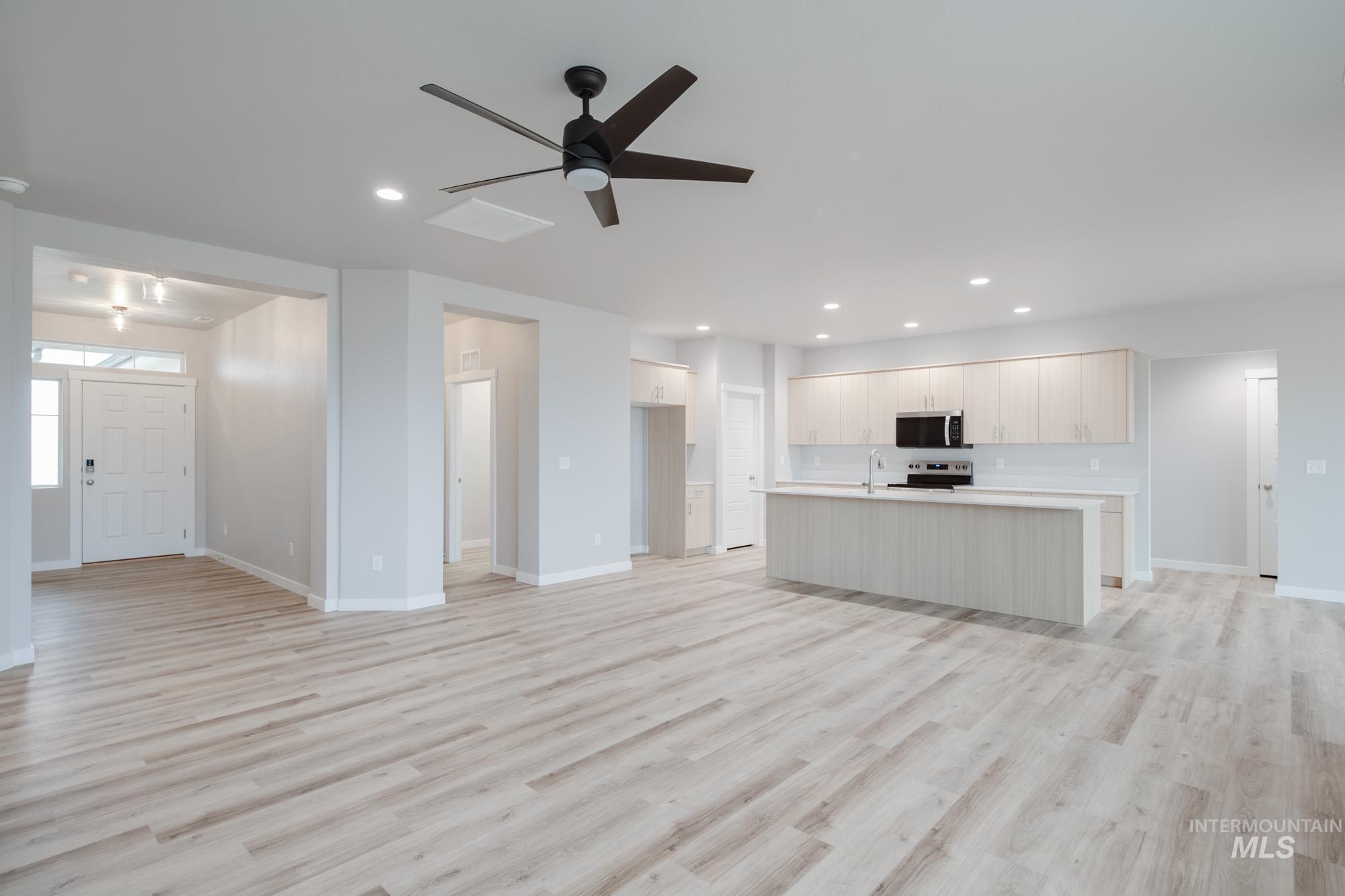 Unfurnished living room featuring light wood finished floors, ceiling fan, and recessed lighting