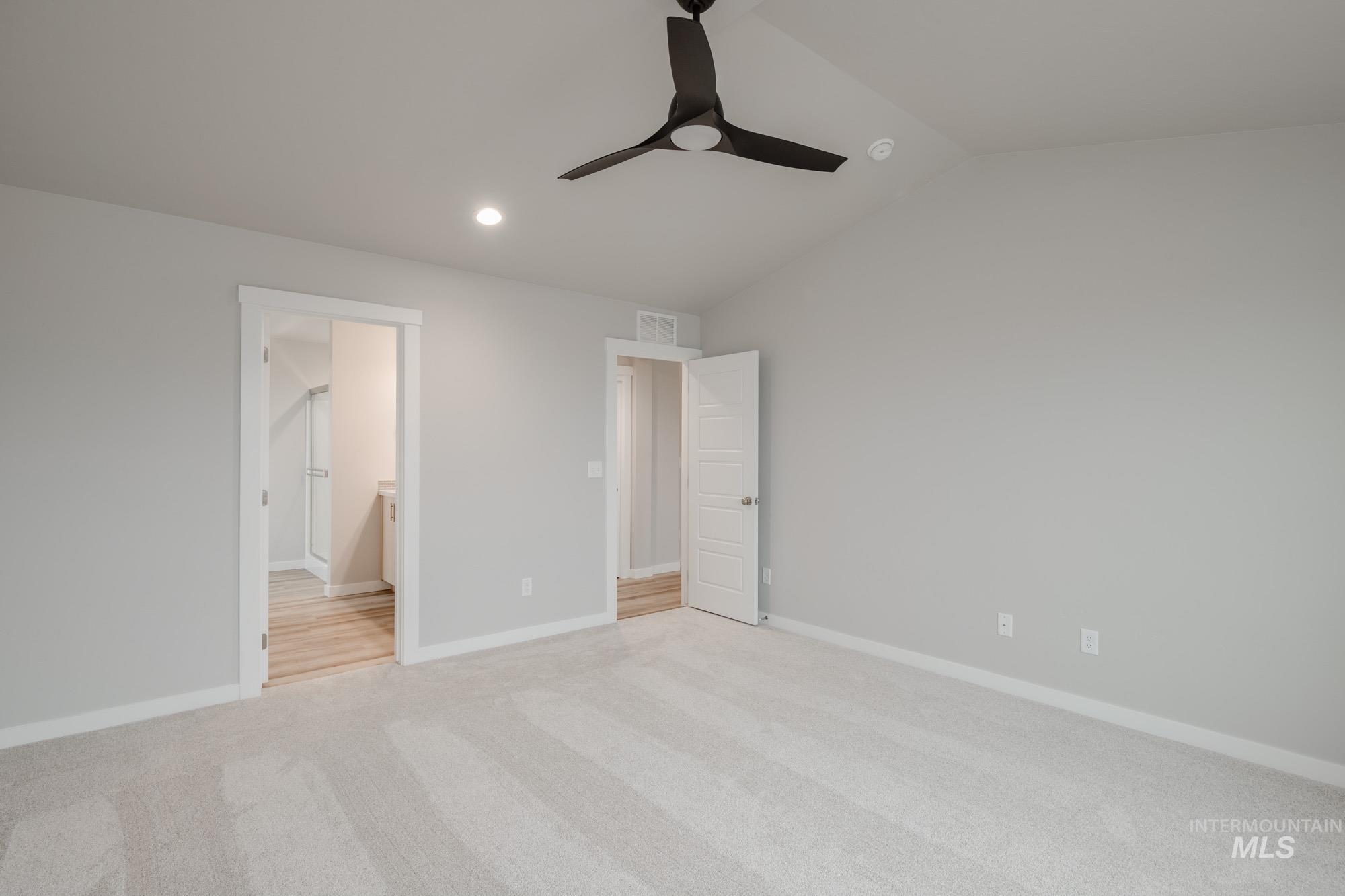 Unfurnished bedroom featuring lofted ceiling, ceiling fan, light colored carpet, recessed lighting, and connected bathroom