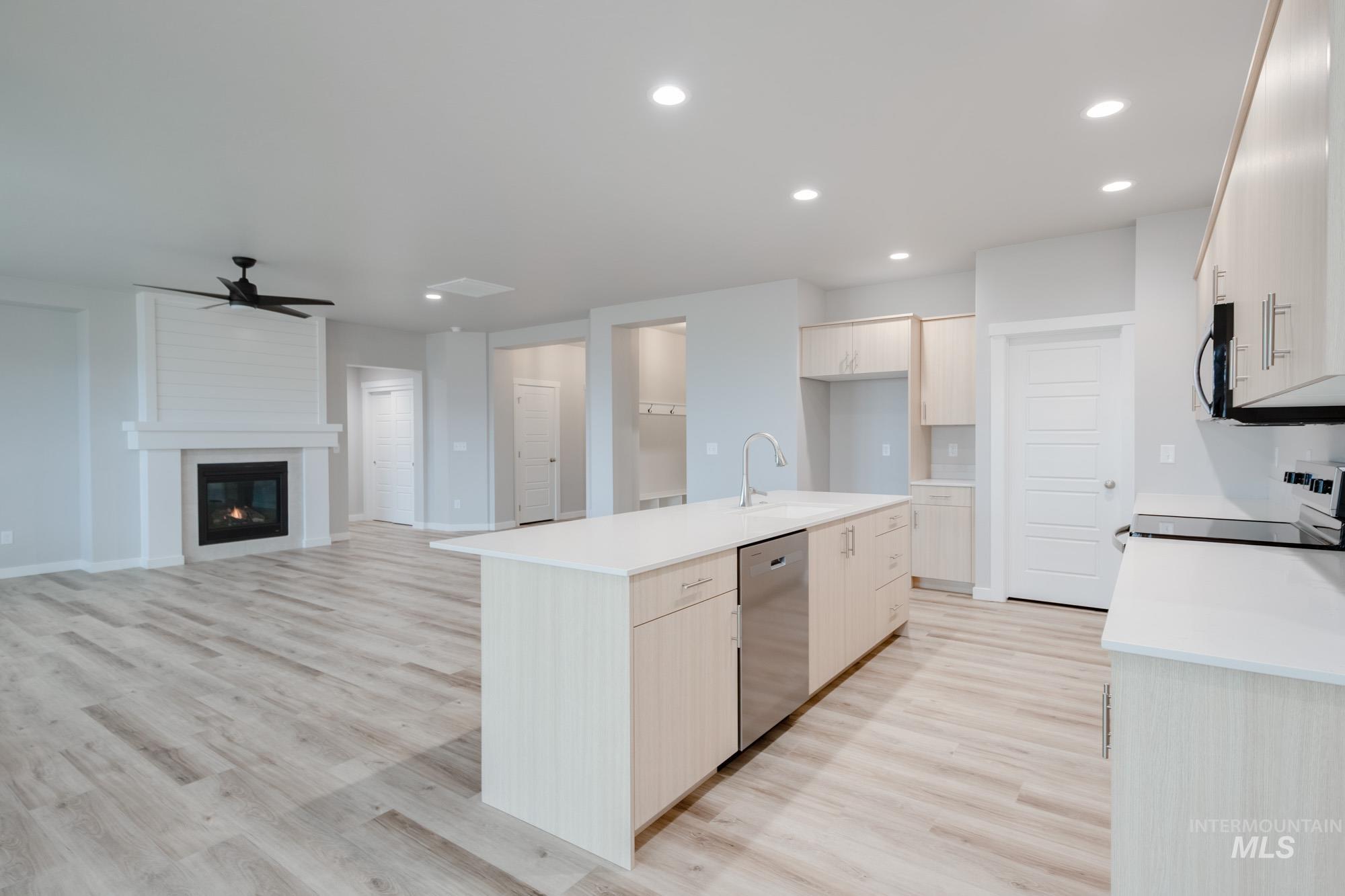 Kitchen with light wood finished floors, a kitchen island with sink, ceiling fan, black / electric stove, and recessed lighting