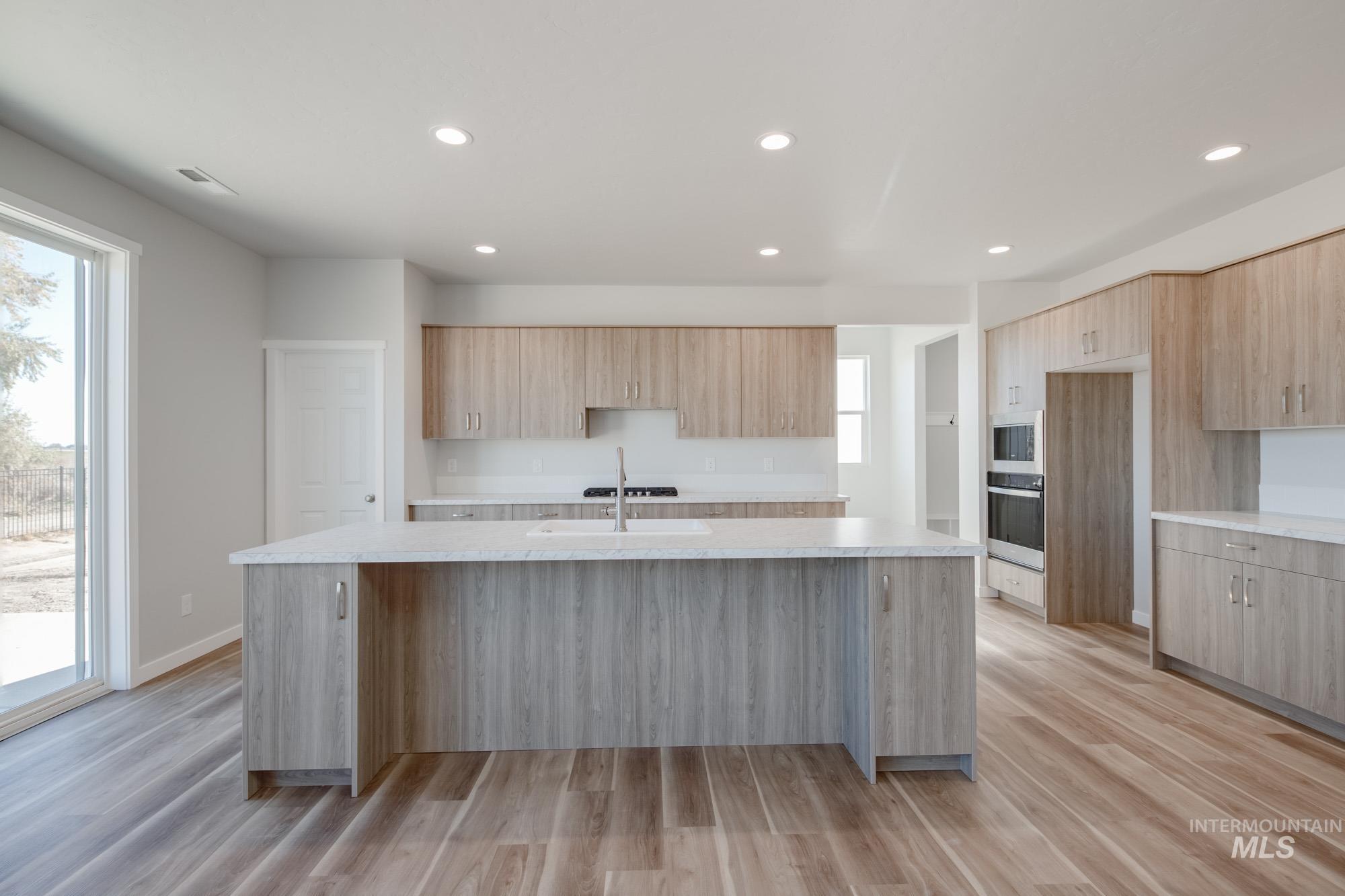 Kitchen with a kitchen island with sink, light wood-style floors, recessed lighting, appliances with stainless steel finishes, and modern cabinets