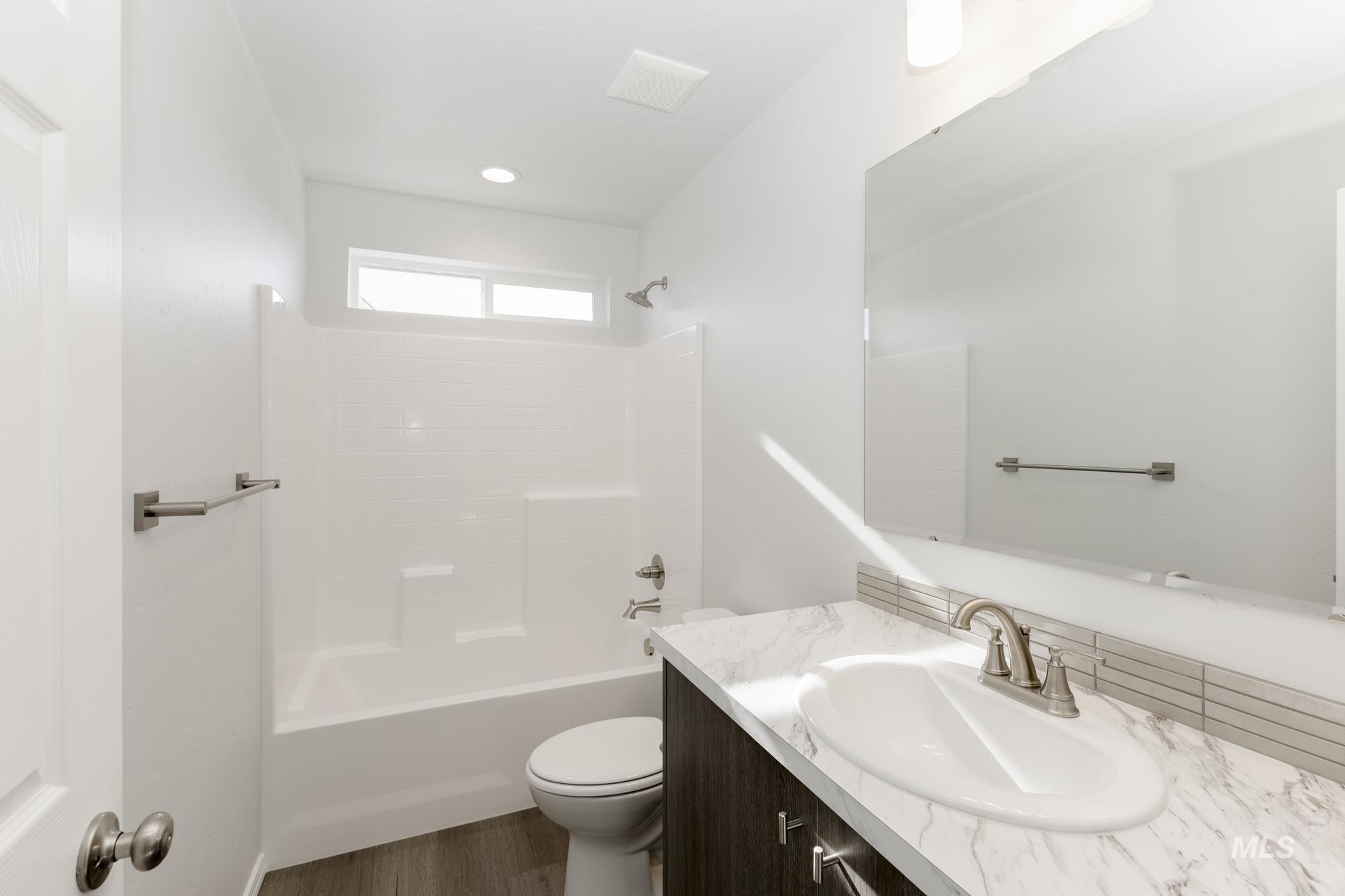 Bathroom featuring shower / bath combination, vanity, and dark wood-style flooring