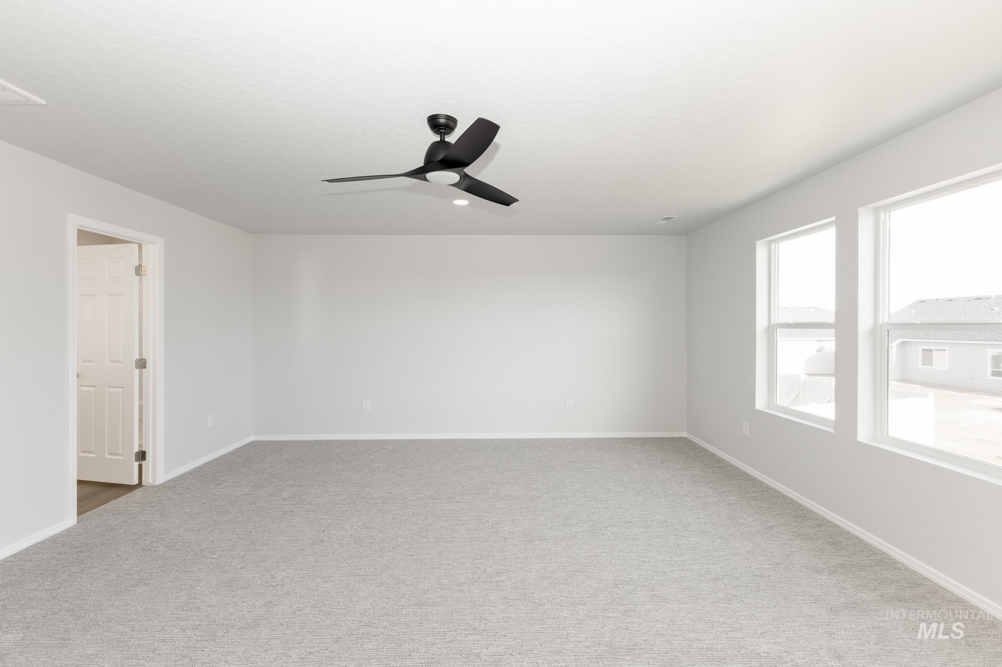 Spare room featuring carpet and ceiling fan