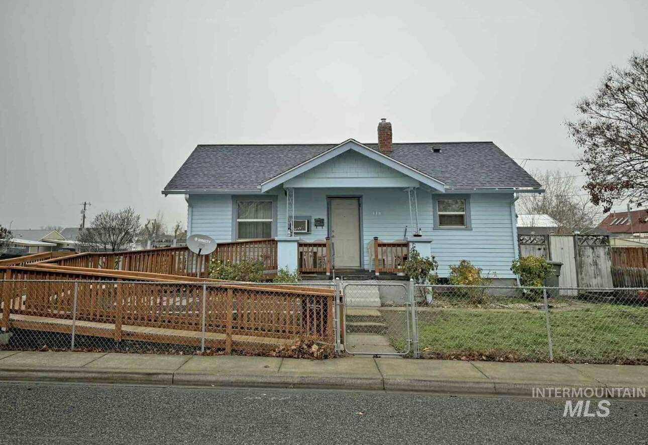 Bungalow-style home with a shingled roof, covered porch, a gate, a chimney, and a fenced front yard
