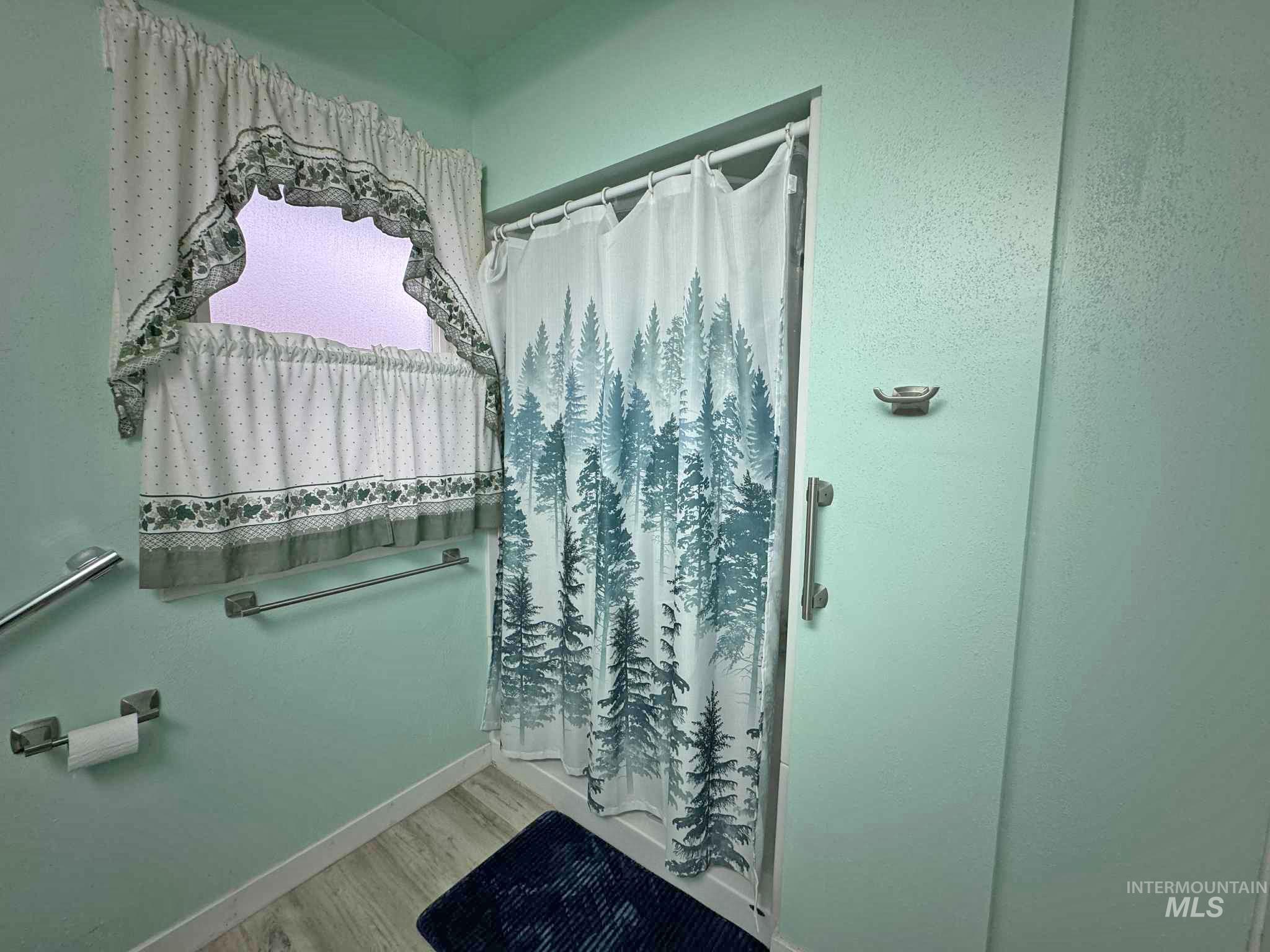 Bathroom featuring a shower with shower curtain and light wood-style floors