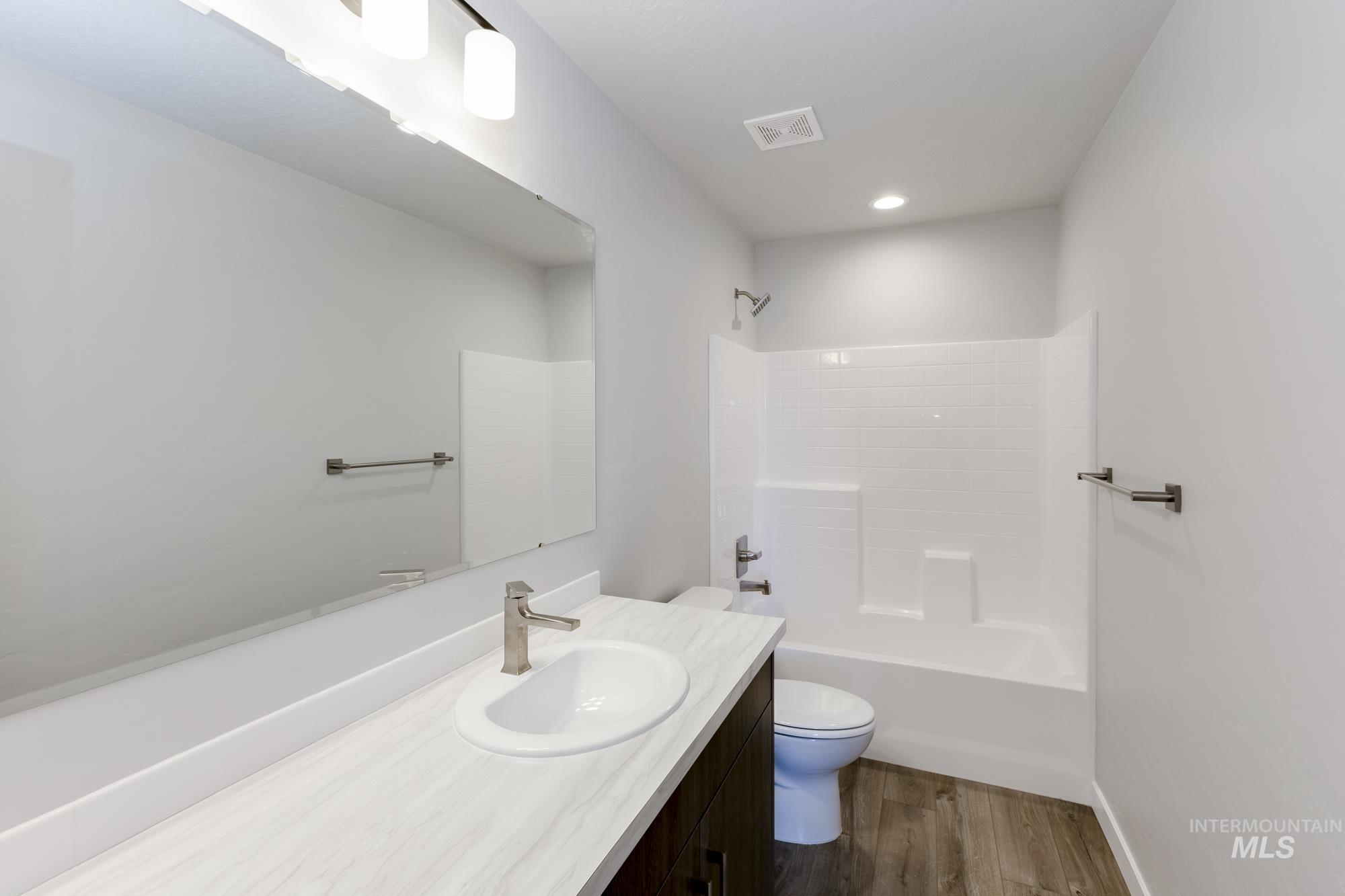 Bathroom with vanity, dark wood-style floors, and shower / washtub combination