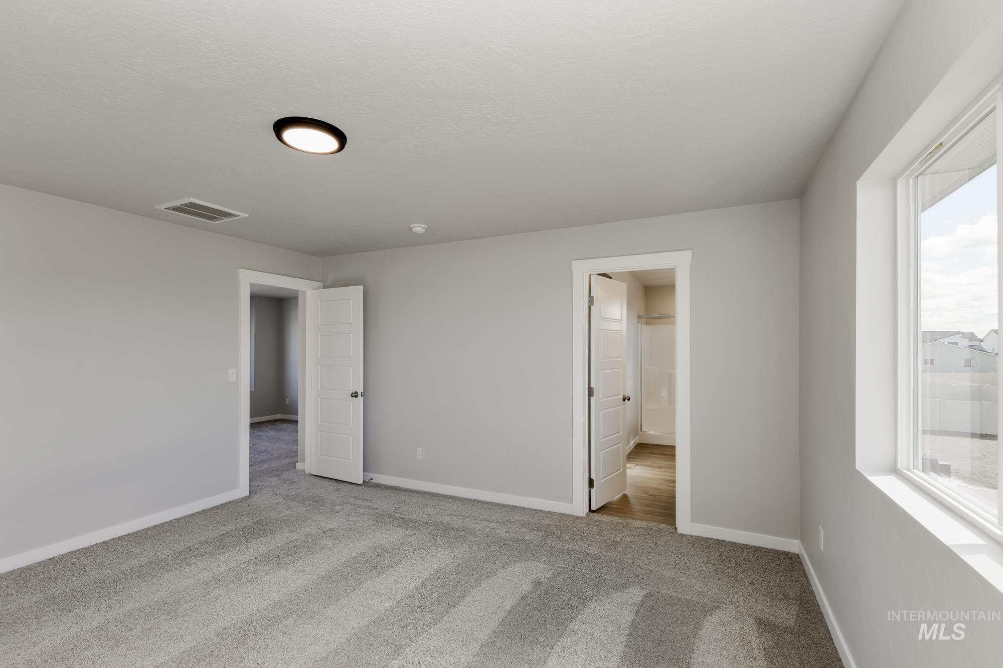 Unfurnished bedroom with light colored carpet and connected bathroom