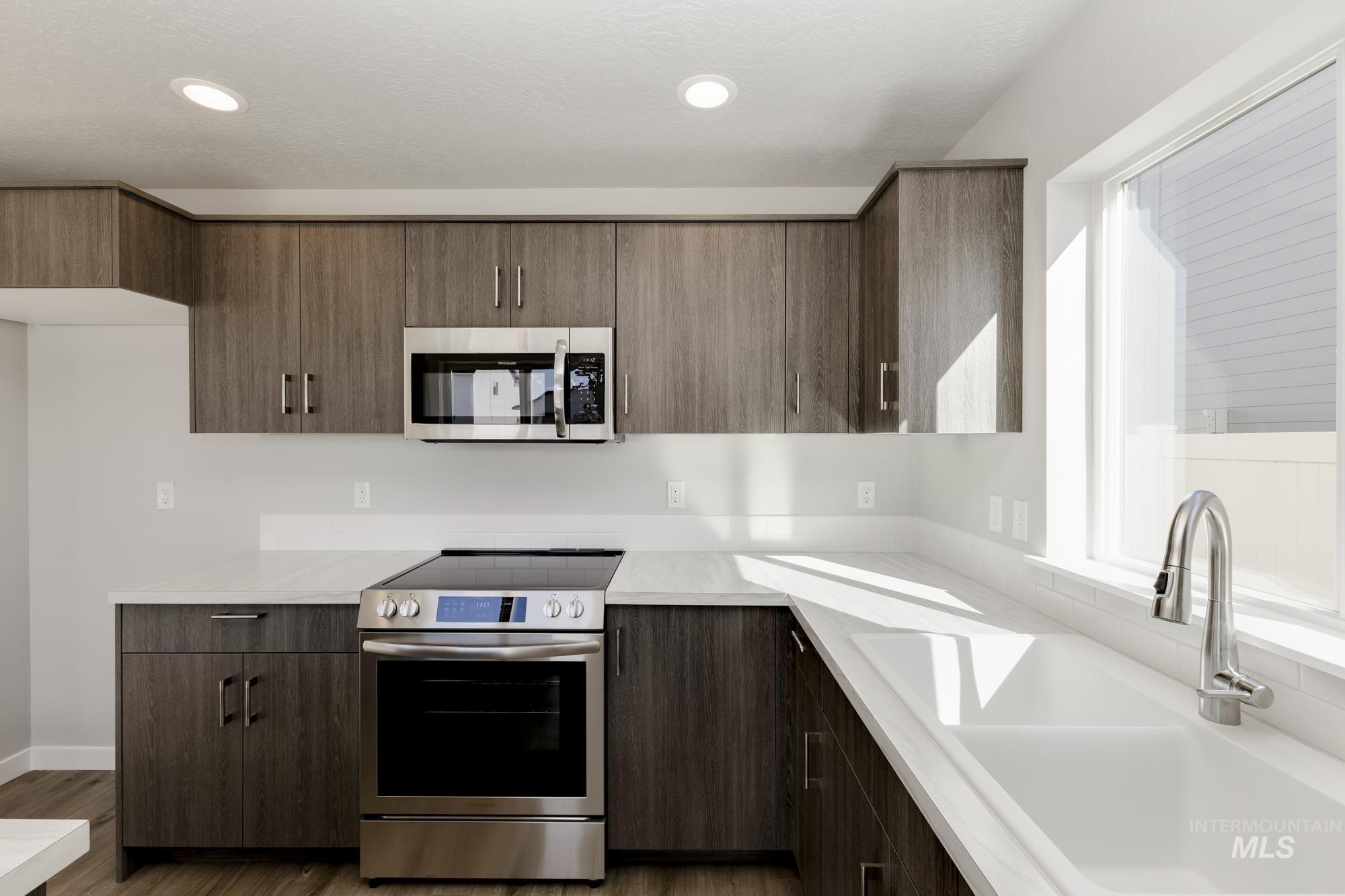 Kitchen featuring stainless steel appliances, dark wood-style flooring, recessed lighting, modern cabinets, and dark brown cabinetry