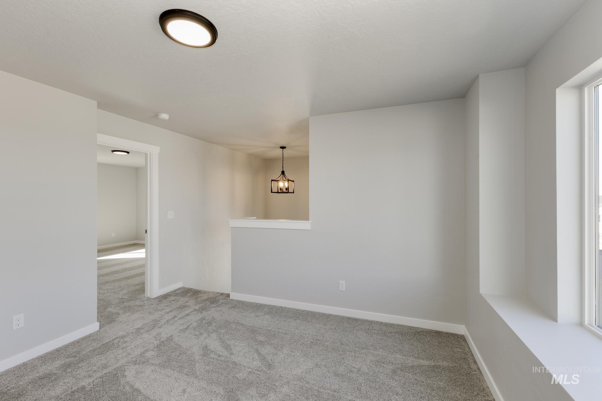 Carpeted spare room with baseboards and a chandelier