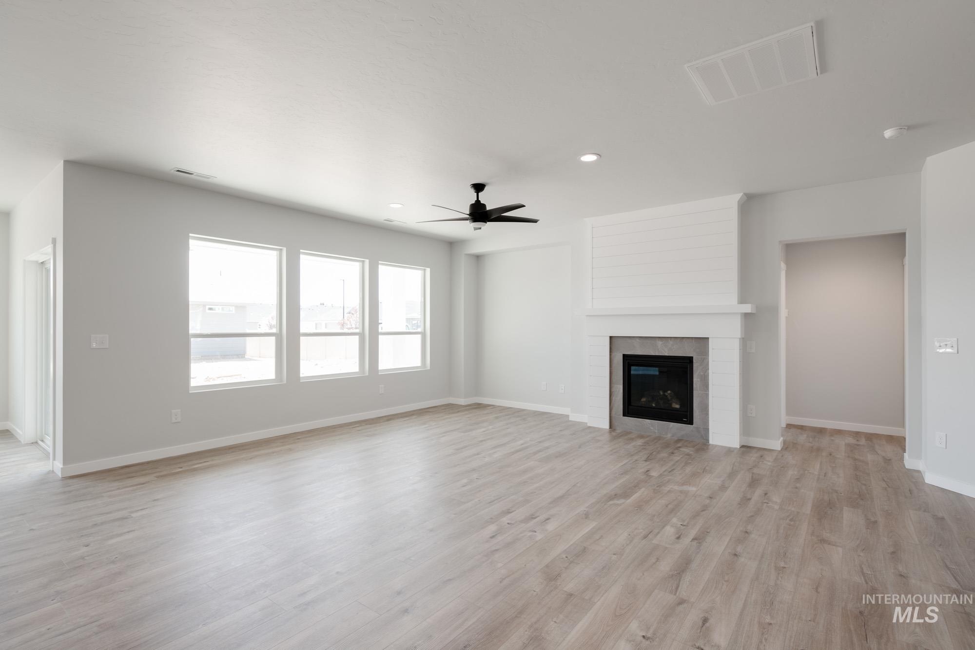 Unfurnished living room with light wood-type flooring, a fireplace, a ceiling fan, and recessed lighting