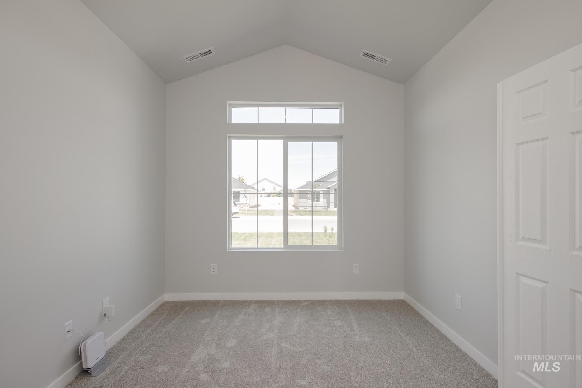 Unfurnished room with vaulted ceiling, light colored carpet, and a residential view