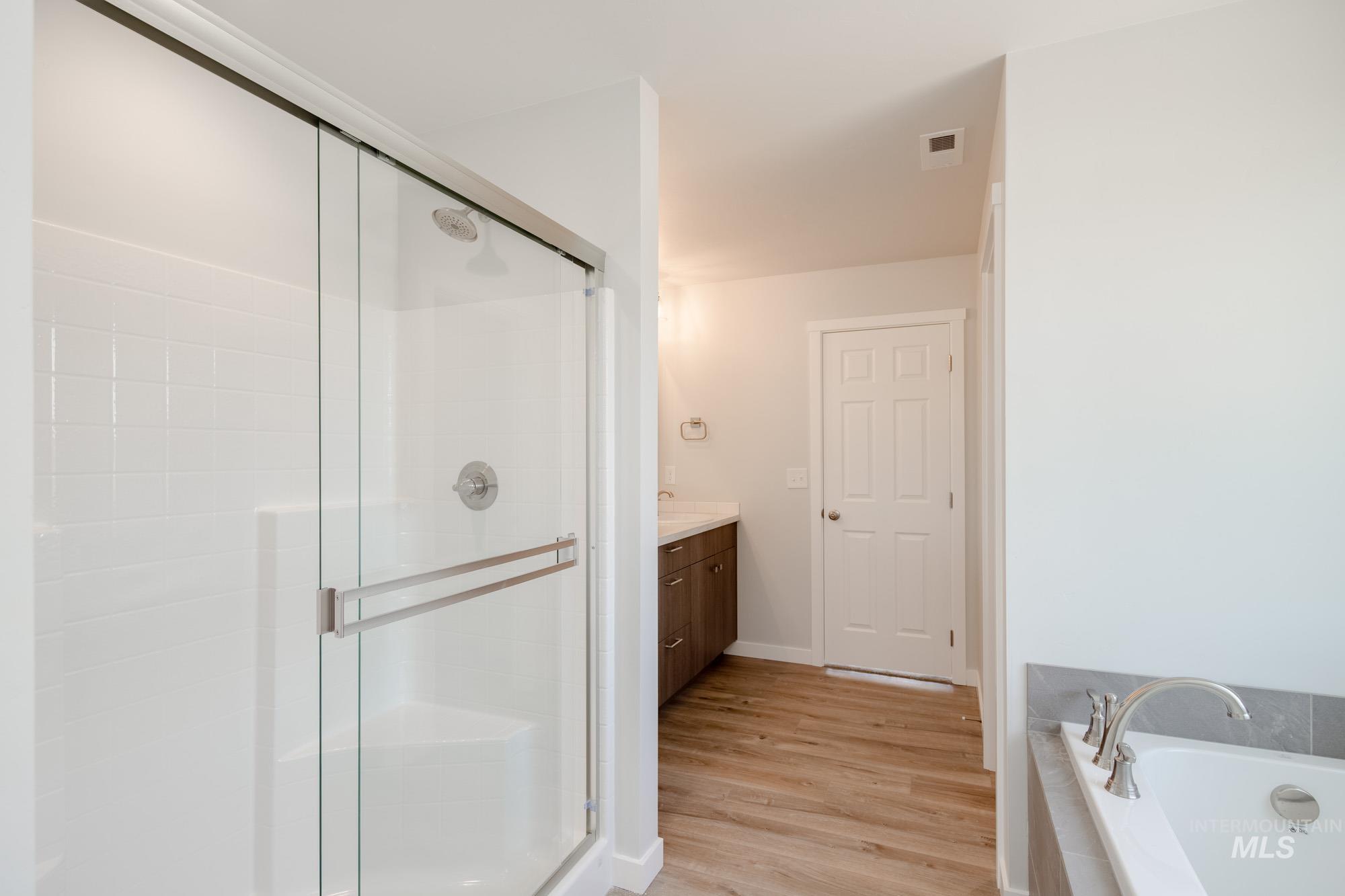 Full bath with vanity, a bath, a shower stall, and light wood-type flooring