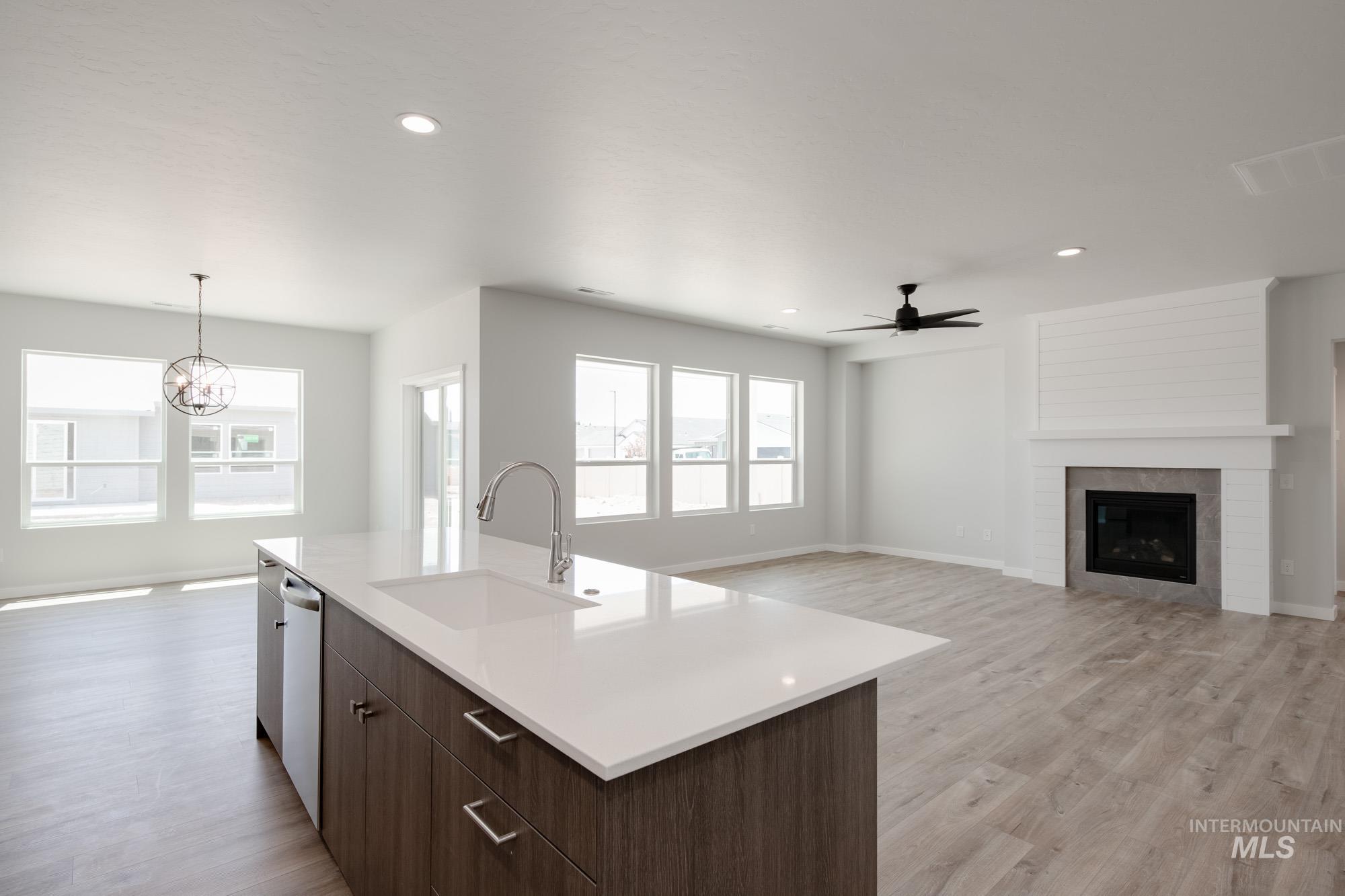 Kitchen with dark brown cabinets, open floor plan, light wood finished floors, a fireplace, and modern cabinets