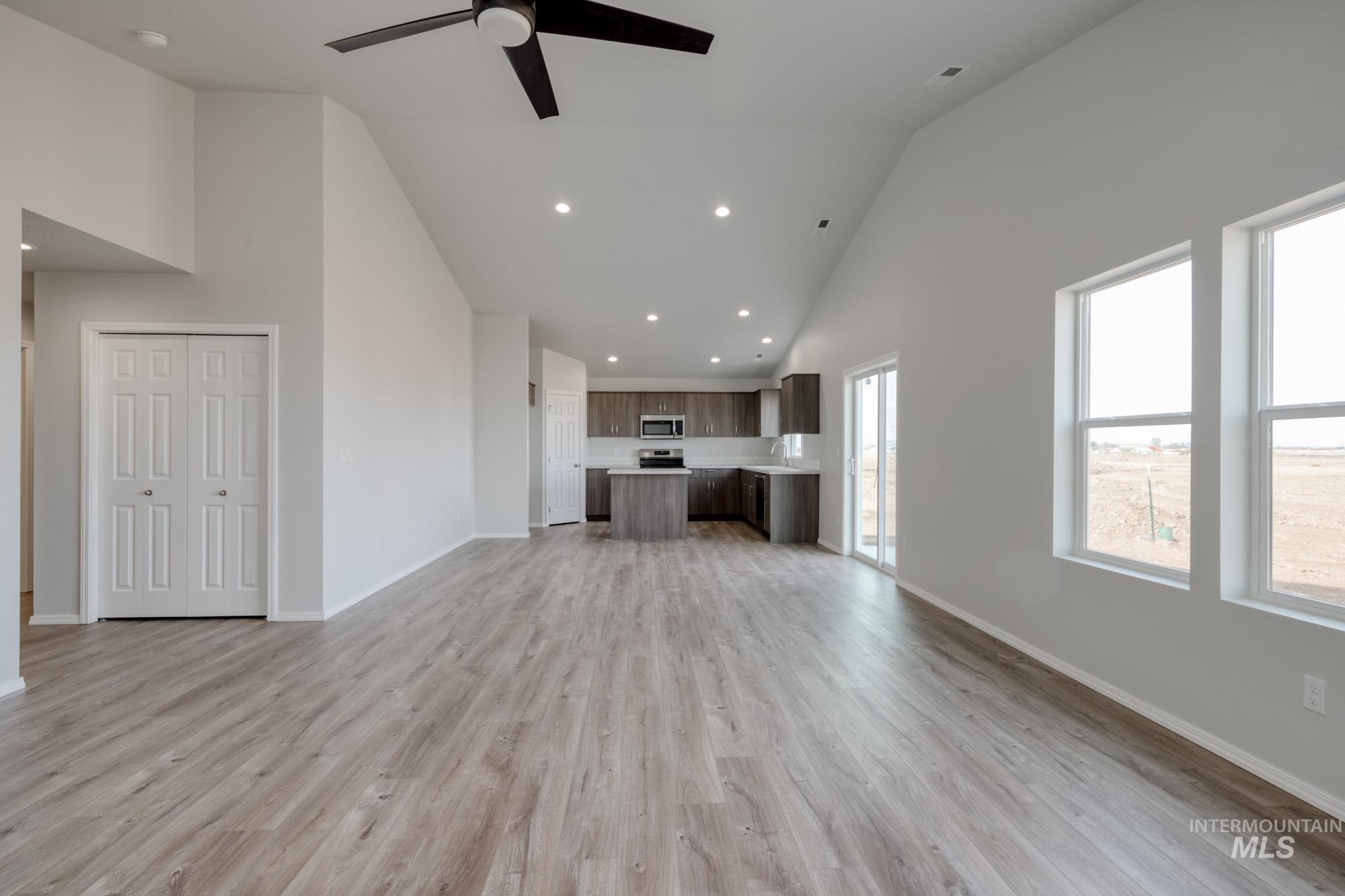 Unfurnished living room featuring high vaulted ceiling, light wood finished floors, recessed lighting, and ceiling fan