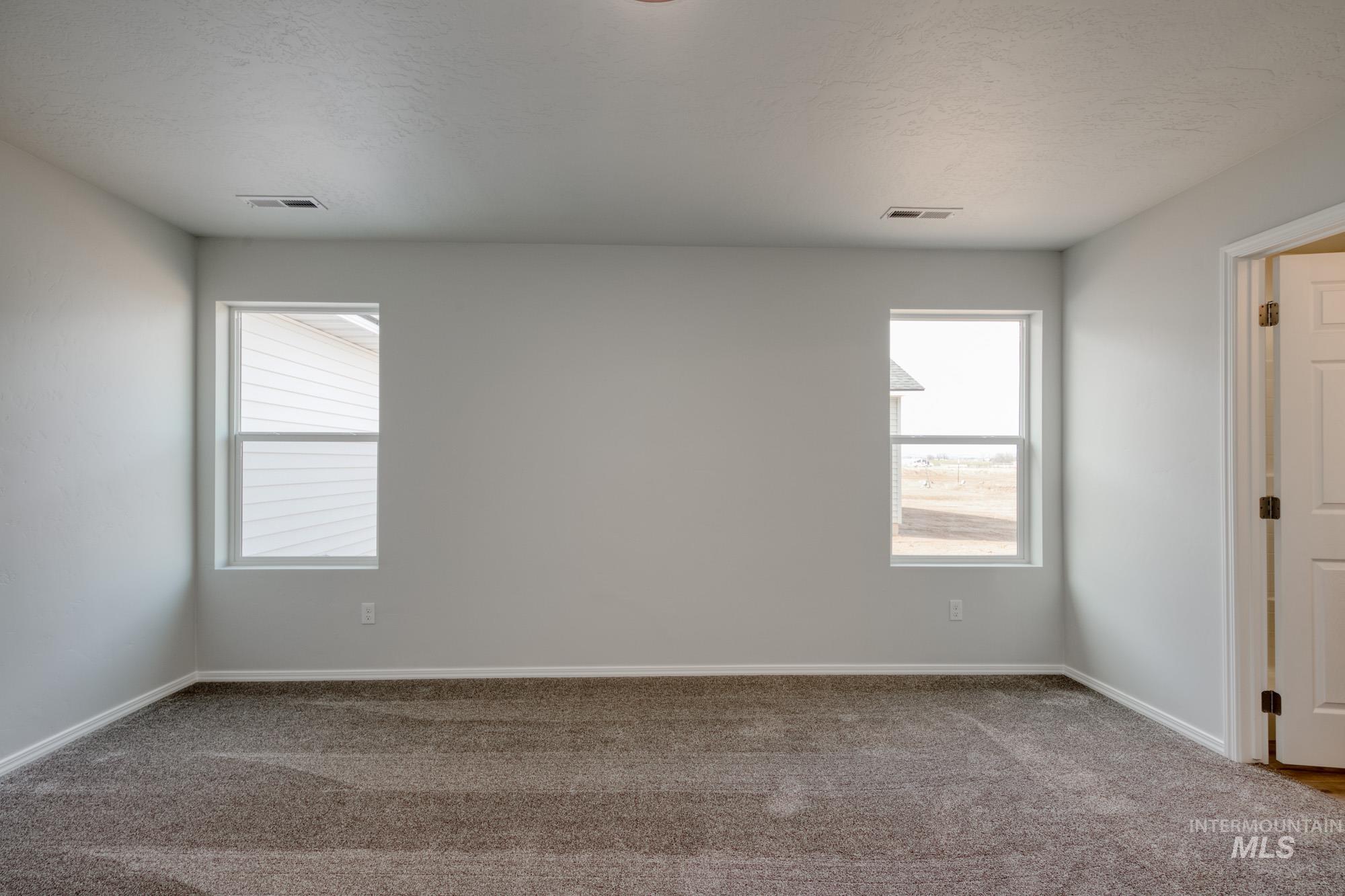 Carpeted spare room with healthy amount of natural light and a textured ceiling