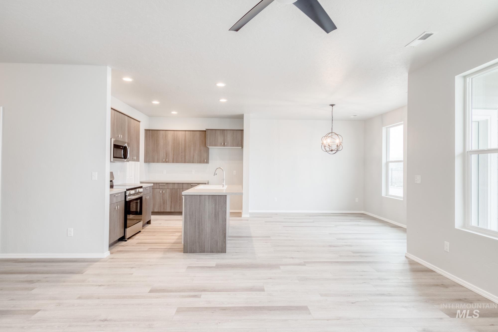 Kitchen with a center island with sink, stainless steel appliances, open floor plan, modern cabinets, and light wood-type flooring