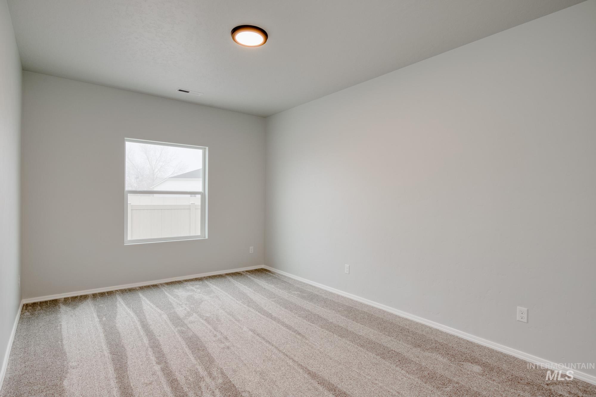 Carpeted spare room featuring baseboards