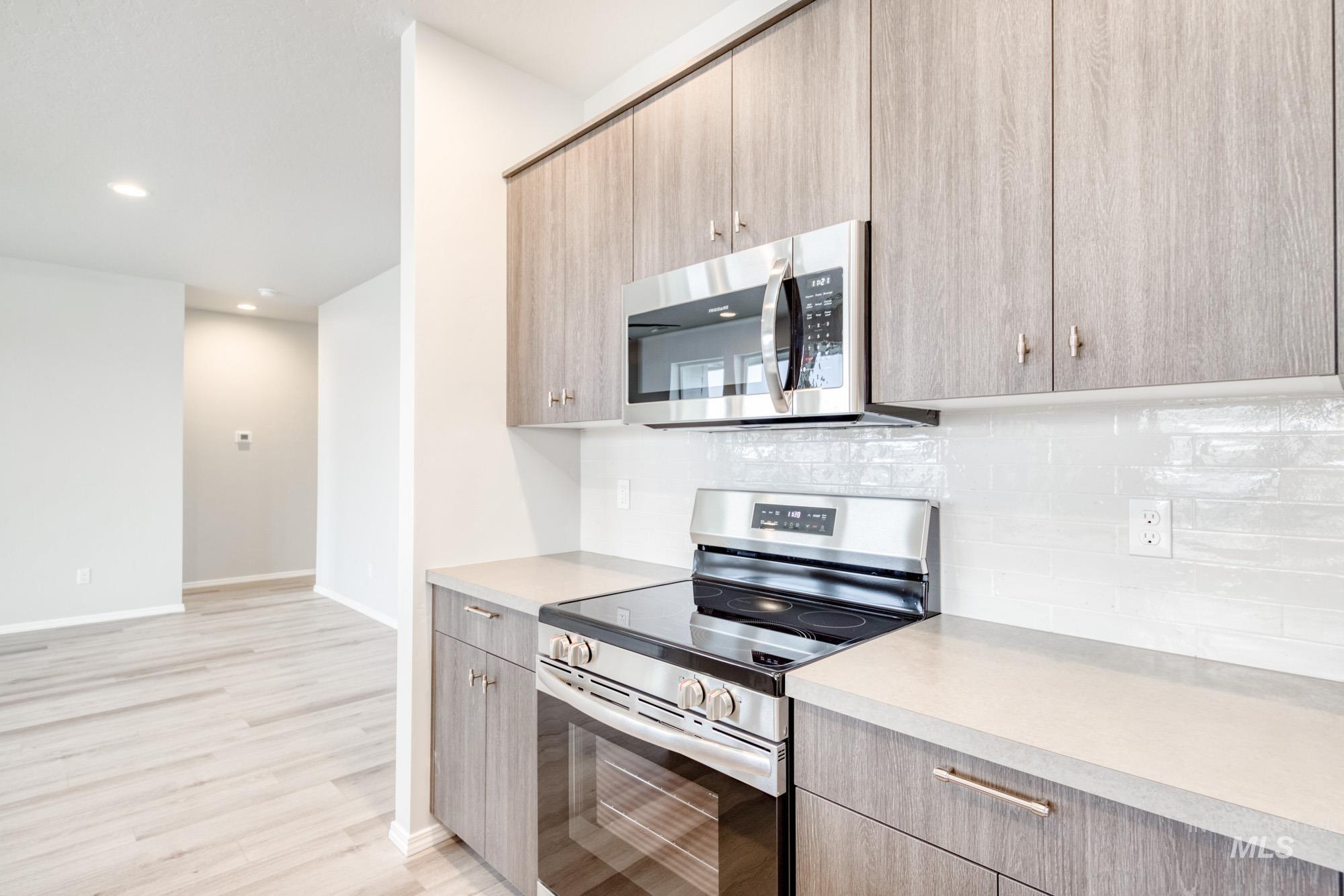 Kitchen with appliances with stainless steel finishes, light countertops, backsplash, modern cabinets, and recessed lighting