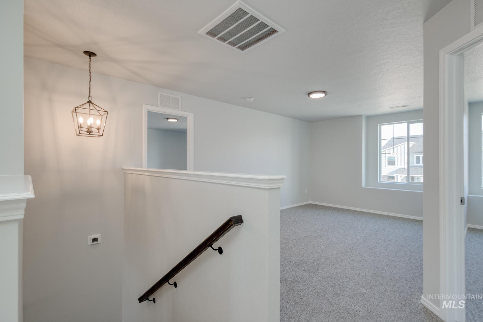 Staircase with carpet flooring and a chandelier