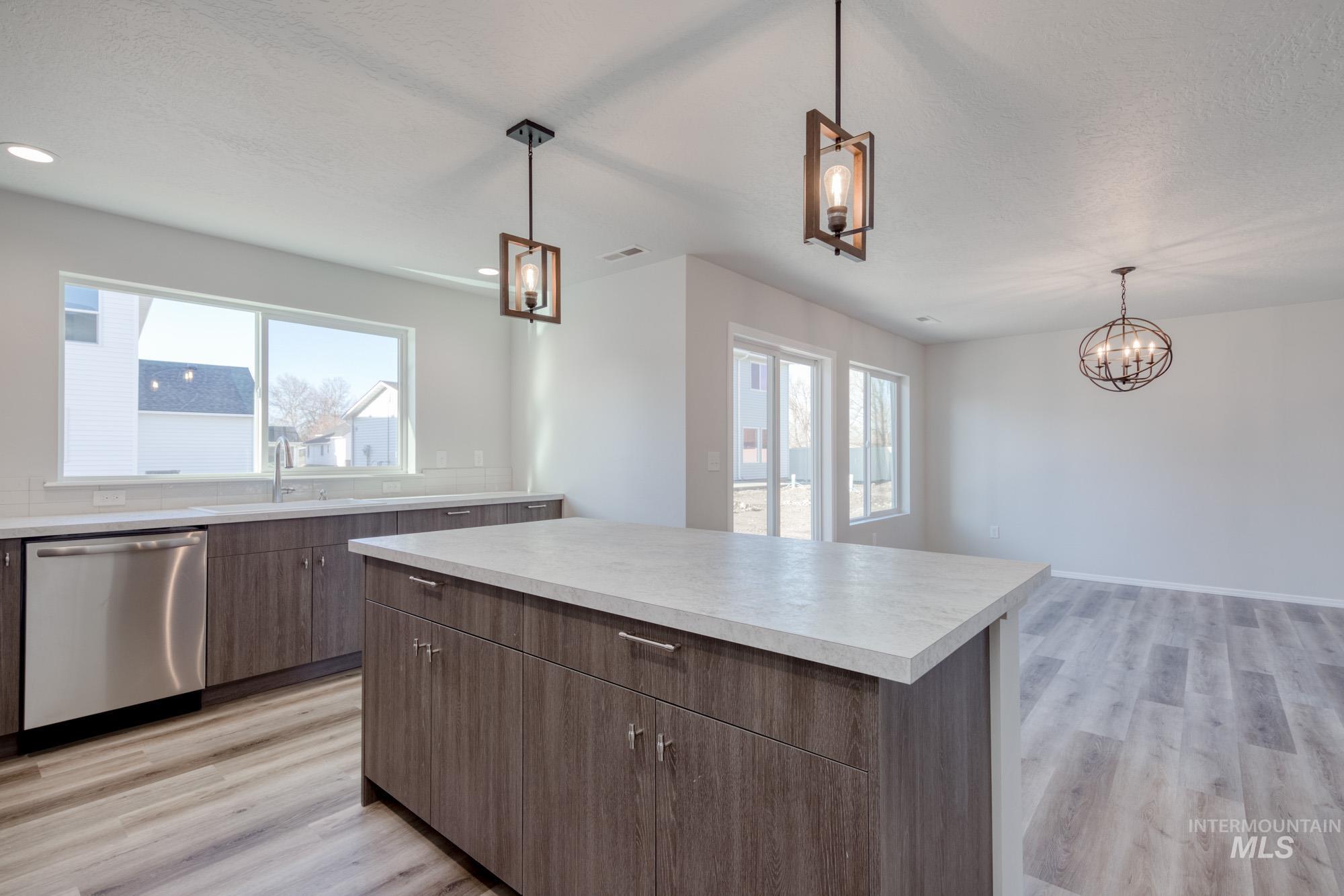 Kitchen featuring plenty of natural light, stainless steel dishwasher, light countertops, light wood-style floors, and a textured ceiling