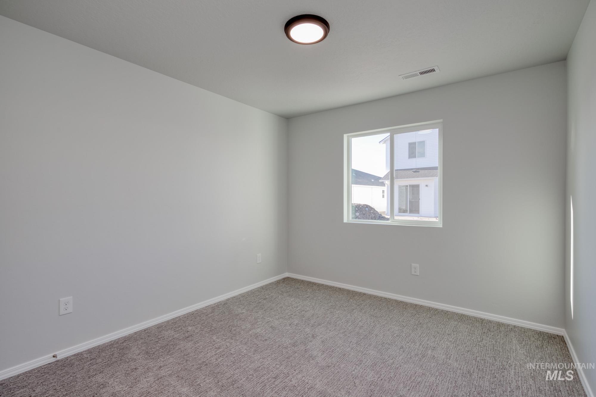 Carpeted spare room featuring baseboards