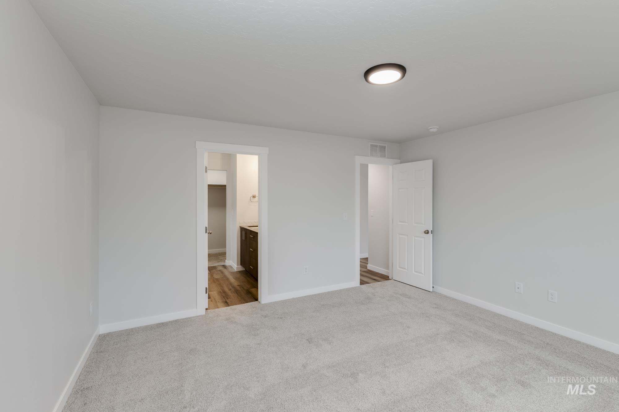 Unfurnished bedroom with light carpet and ensuite bath