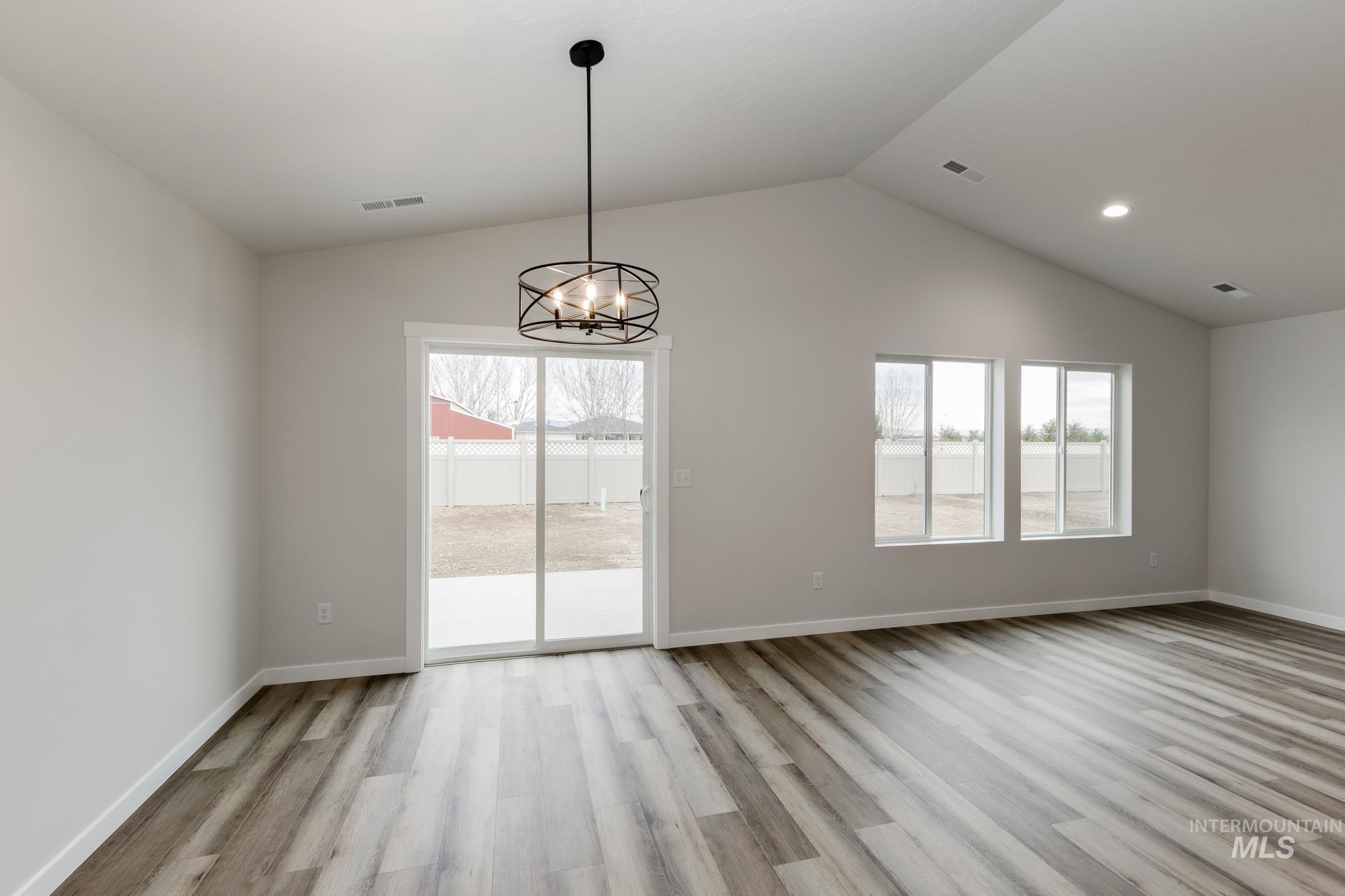Unfurnished dining area featuring a chandelier, light wood-style floors, and lofted ceiling