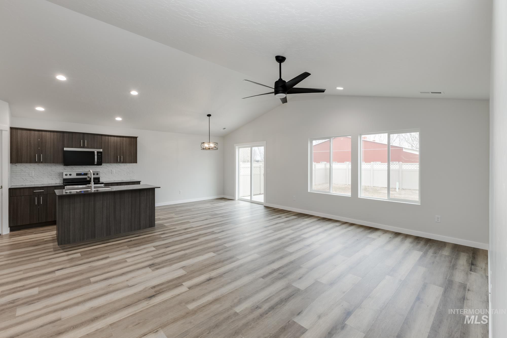 Kitchen featuring open floor plan, dark brown cabinetry, a kitchen island with sink, vaulted ceiling, and recessed lighting
