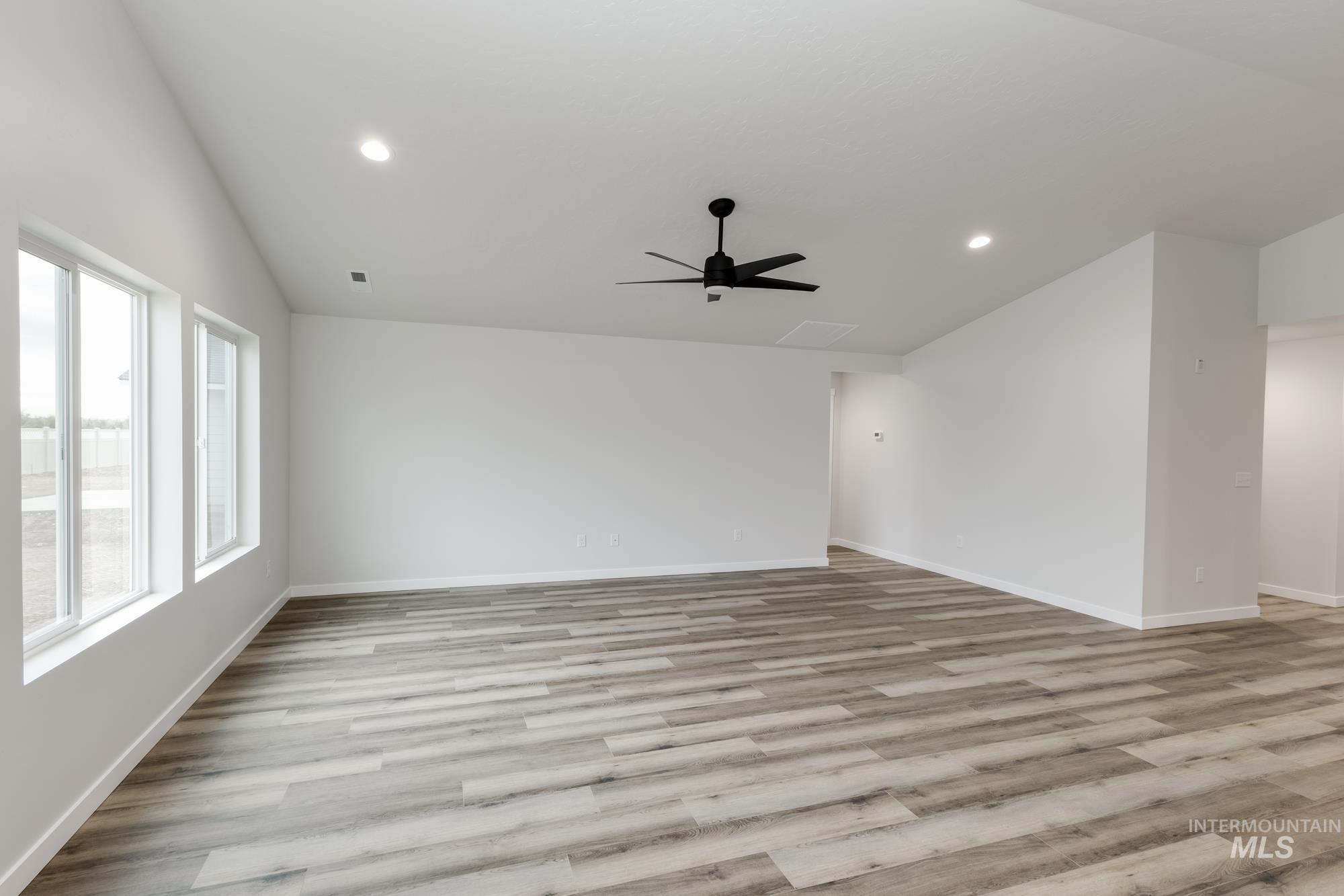 Spare room with vaulted ceiling, light wood-style flooring, a ceiling fan, and recessed lighting