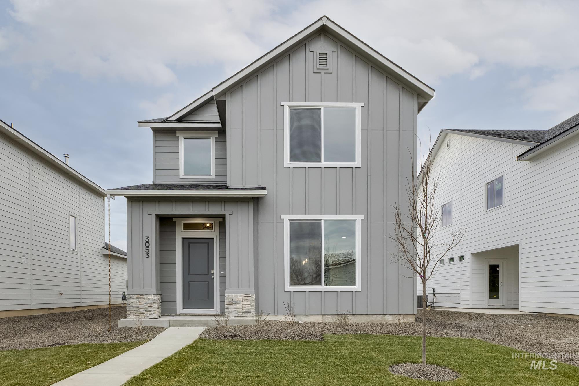 Modern farmhouse with board and batten siding, a front yard, and roof with shingles